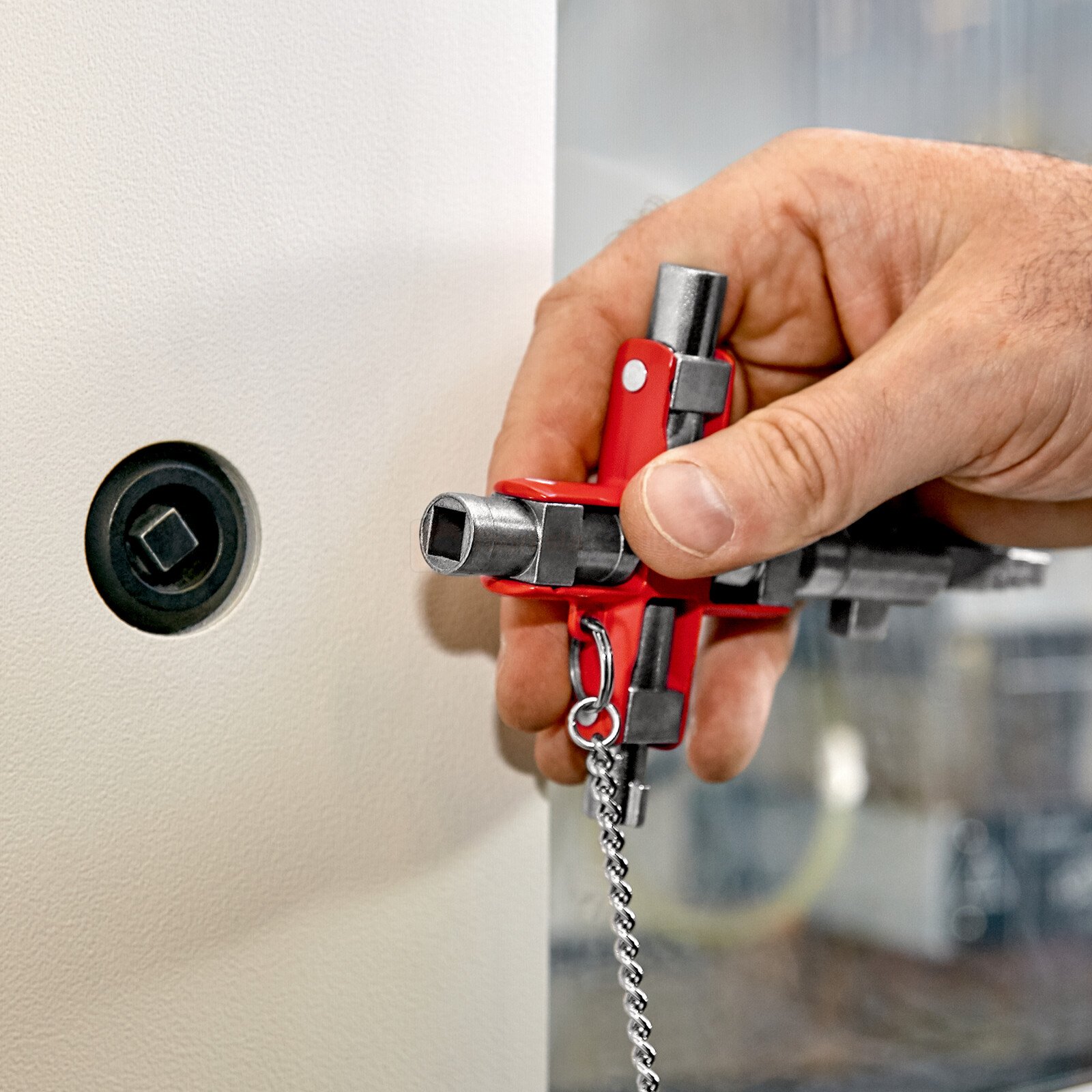 Pildil on näha, kuidas käsi hoiab Knipex universaalset võtit "Construction", et avada standardset kappi.
