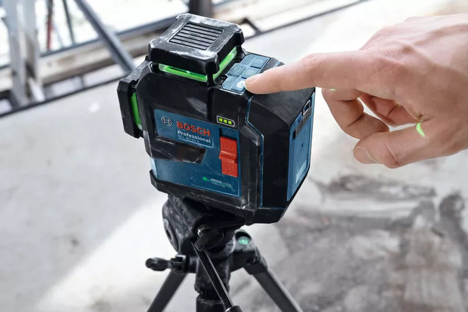 Pildil on Bosch joonlaser GLL 80-33 G, mida kasutaja sisse lülitab, näidates rohelist laserkiirt.