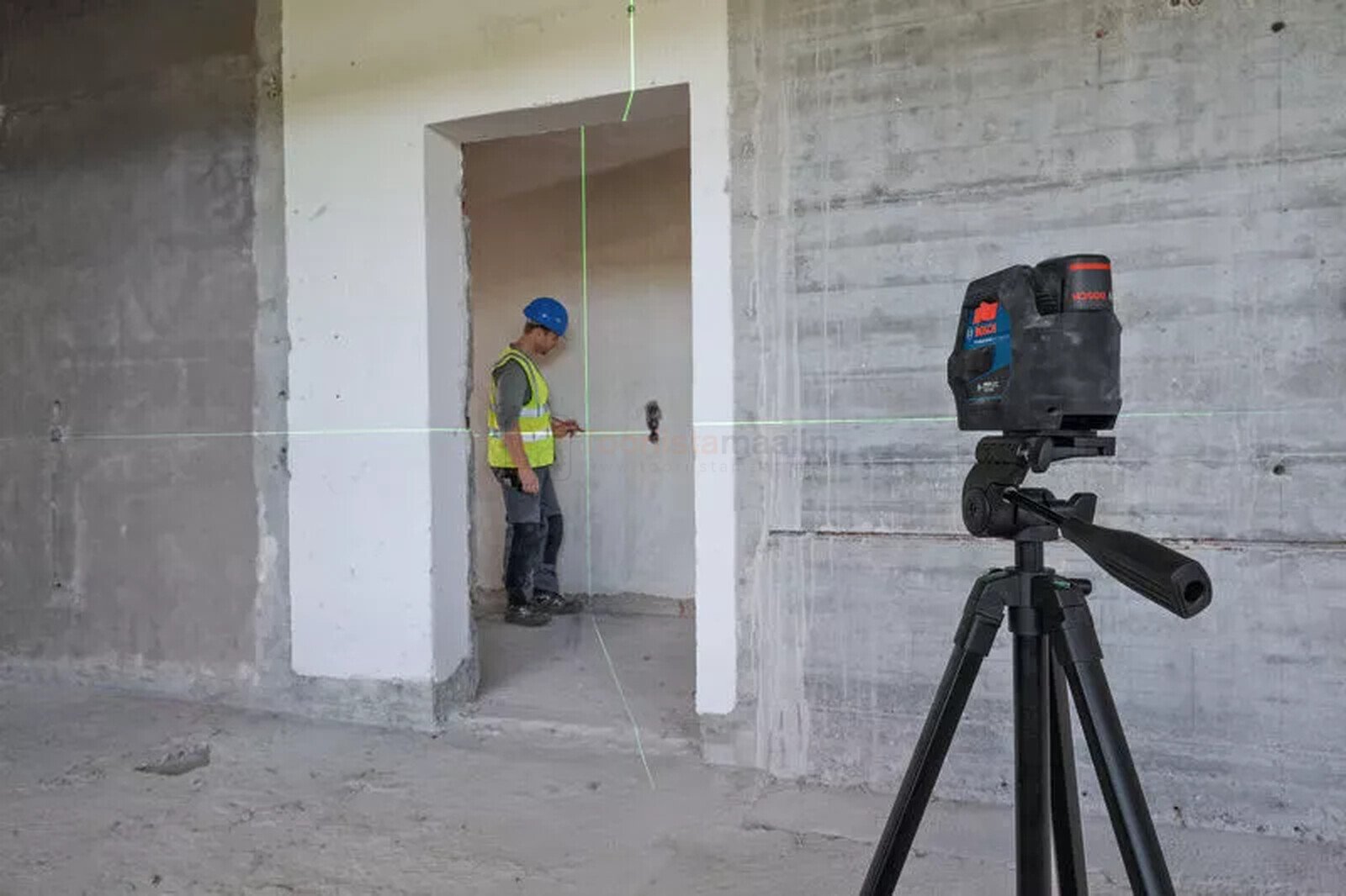 Pildil on ehitustööline, kes kasutab Bosch punktristlaserit GCL 12V-50-22 CG, et joondada seinu ja uksi.