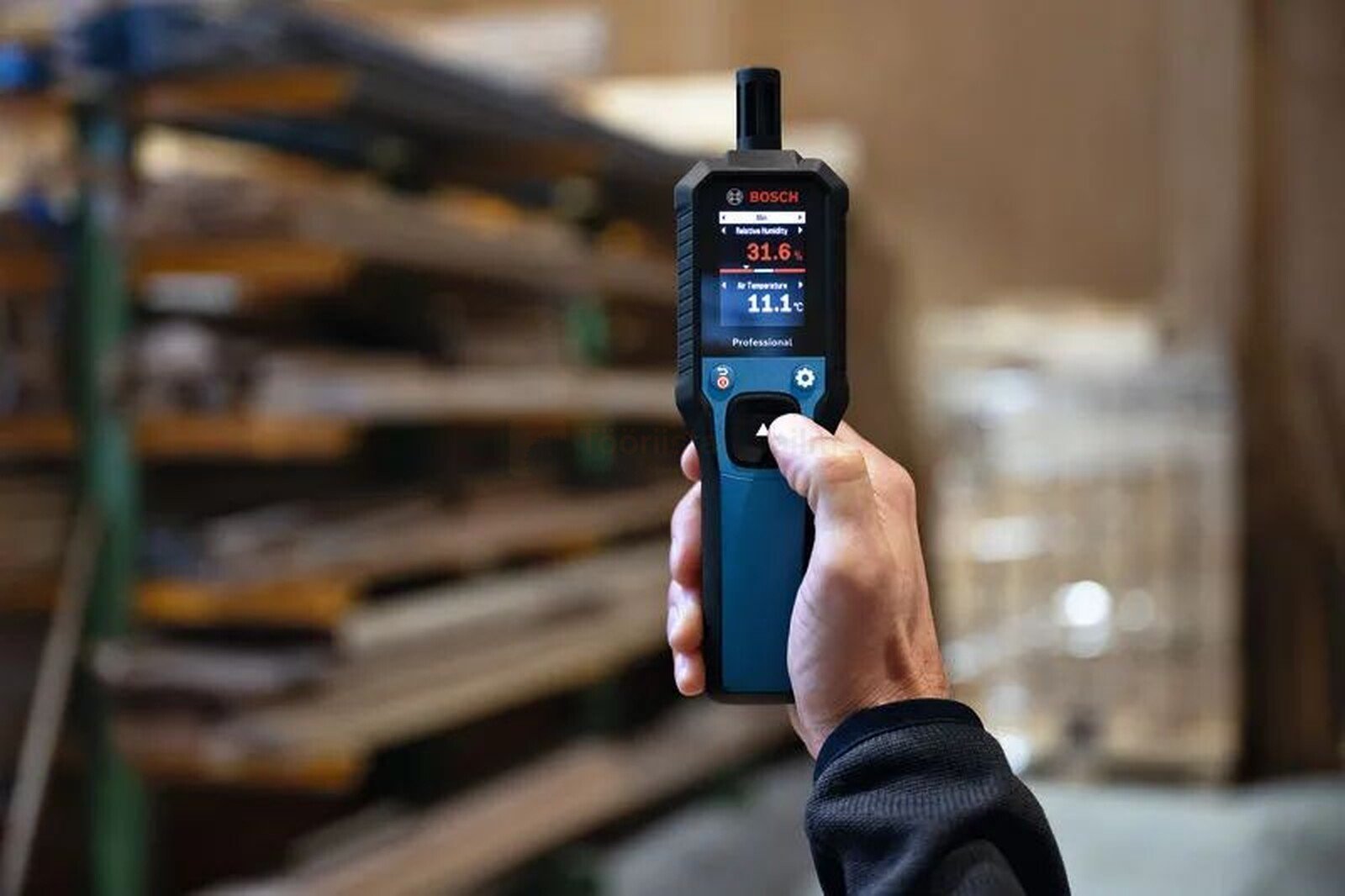 Pildil on näha kätt, mis hoiab Bosch GDH 1-17 termo-hügromeetrit, mille ekraan näitab mõõteväärtusi.