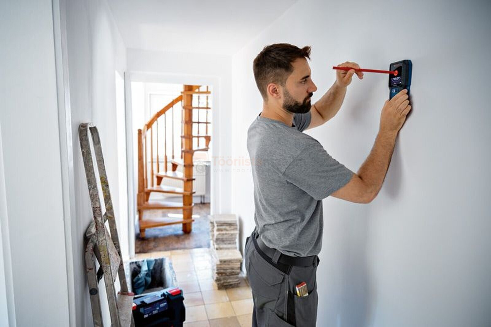 Pildil on mees, kes kasutab Bosch seinaskannerit, et seinal markeeringuid teha.