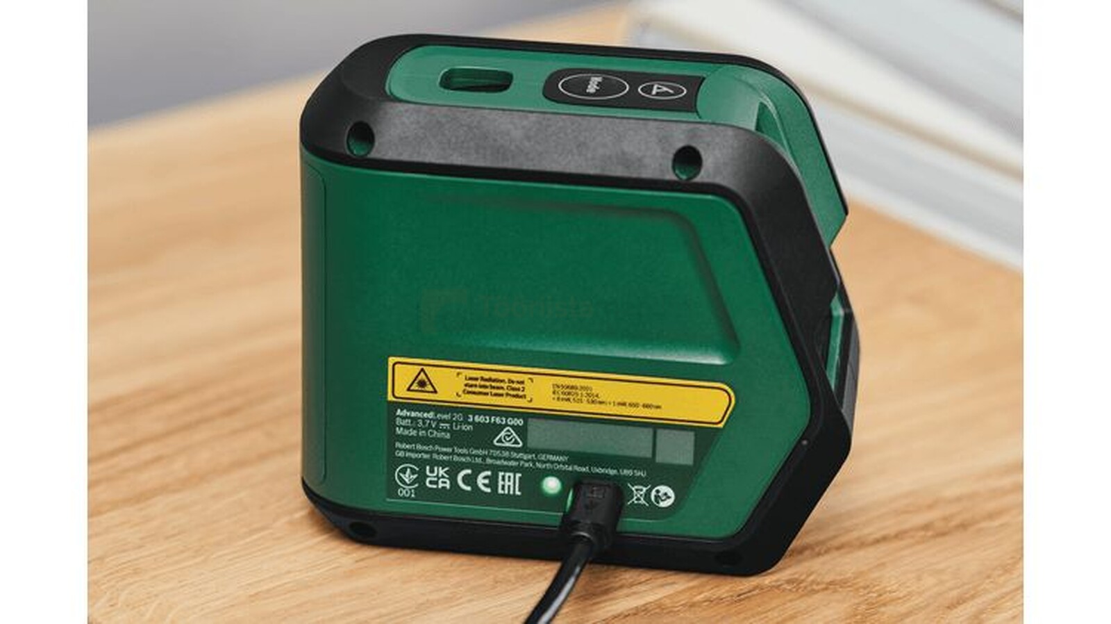Pildil on näha Bosch ristjoonlaser AdvancedLevel 2G, mis on laetud ja asetseb puidust laual.