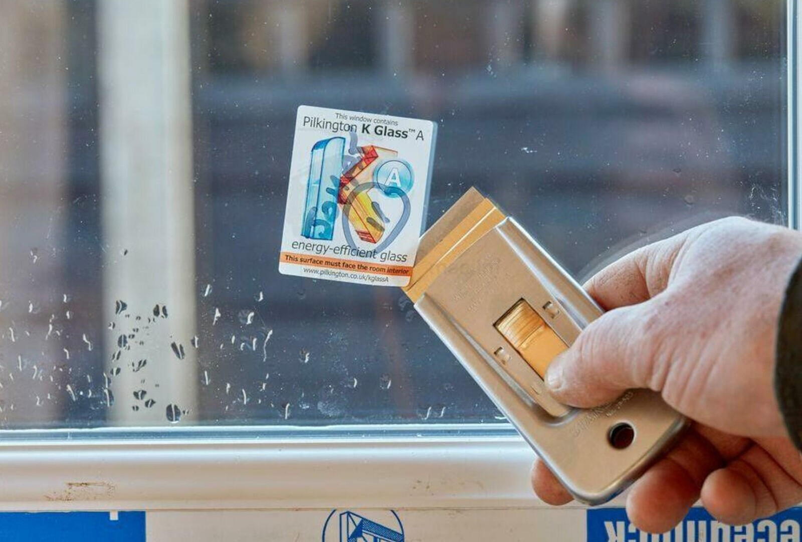 Pildil on näha, kuidas inimene kasutab Stanley 40 mm kaabitsat, et eemaldada kleebist klaasilt.