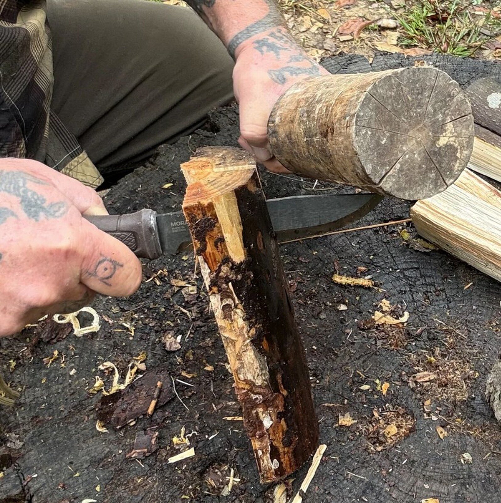 Pildil on mees, kes kasutab Morakniv Garberg Grand matkanuga BlackBlade™ puidu lõhkumiseks, lüües noaga puidu sisse.