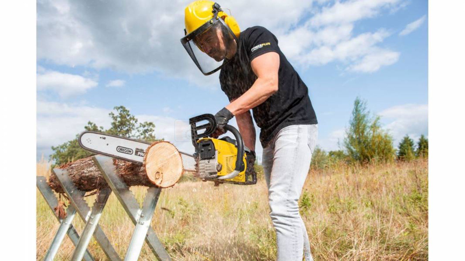Pildil on mees, kes kasutab Powerplus X mootorsaagi POWXG10231, et saagida puidulõiku.