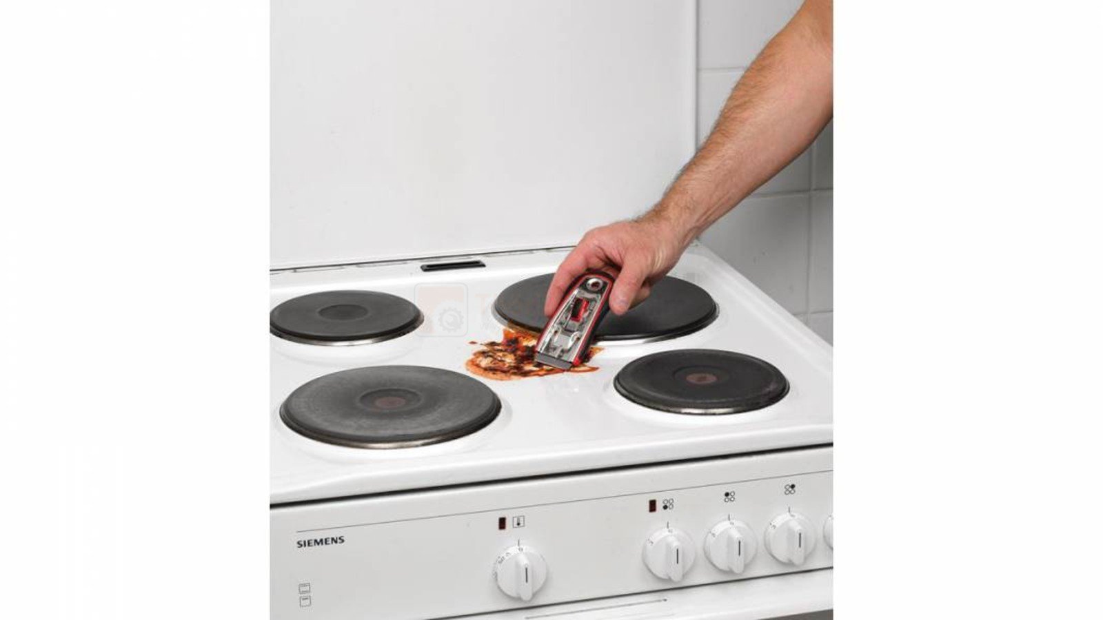 Pildil on näha, kuidas inimene kasutab Kreator 40 mm kaabitsat pliidiplaadilt mustuse eemaldamiseks.