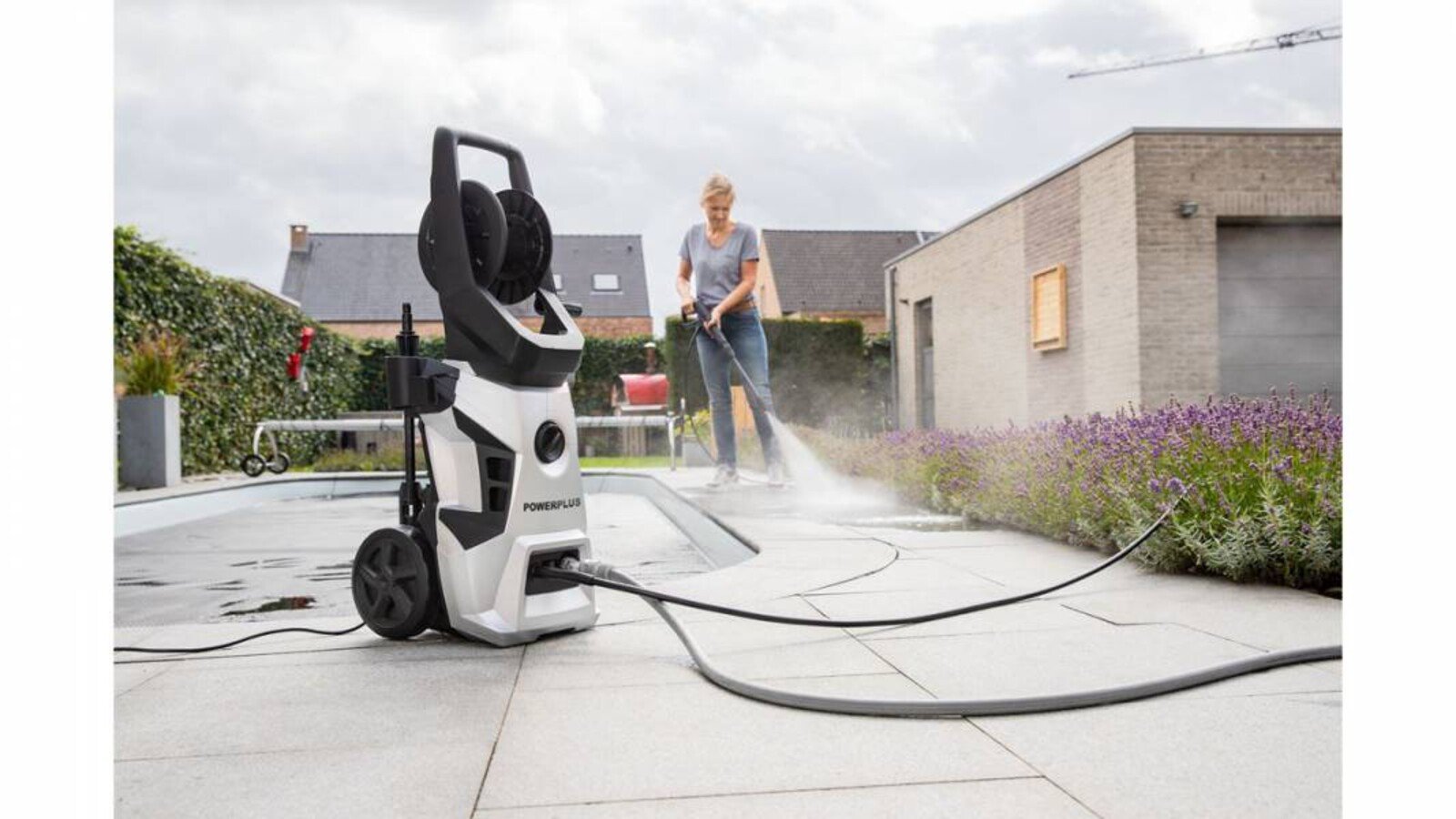 Pildil on näha naist, kes kasutab Powerplus X survepesurit POWXG90500, et puhastada väliterrassi.