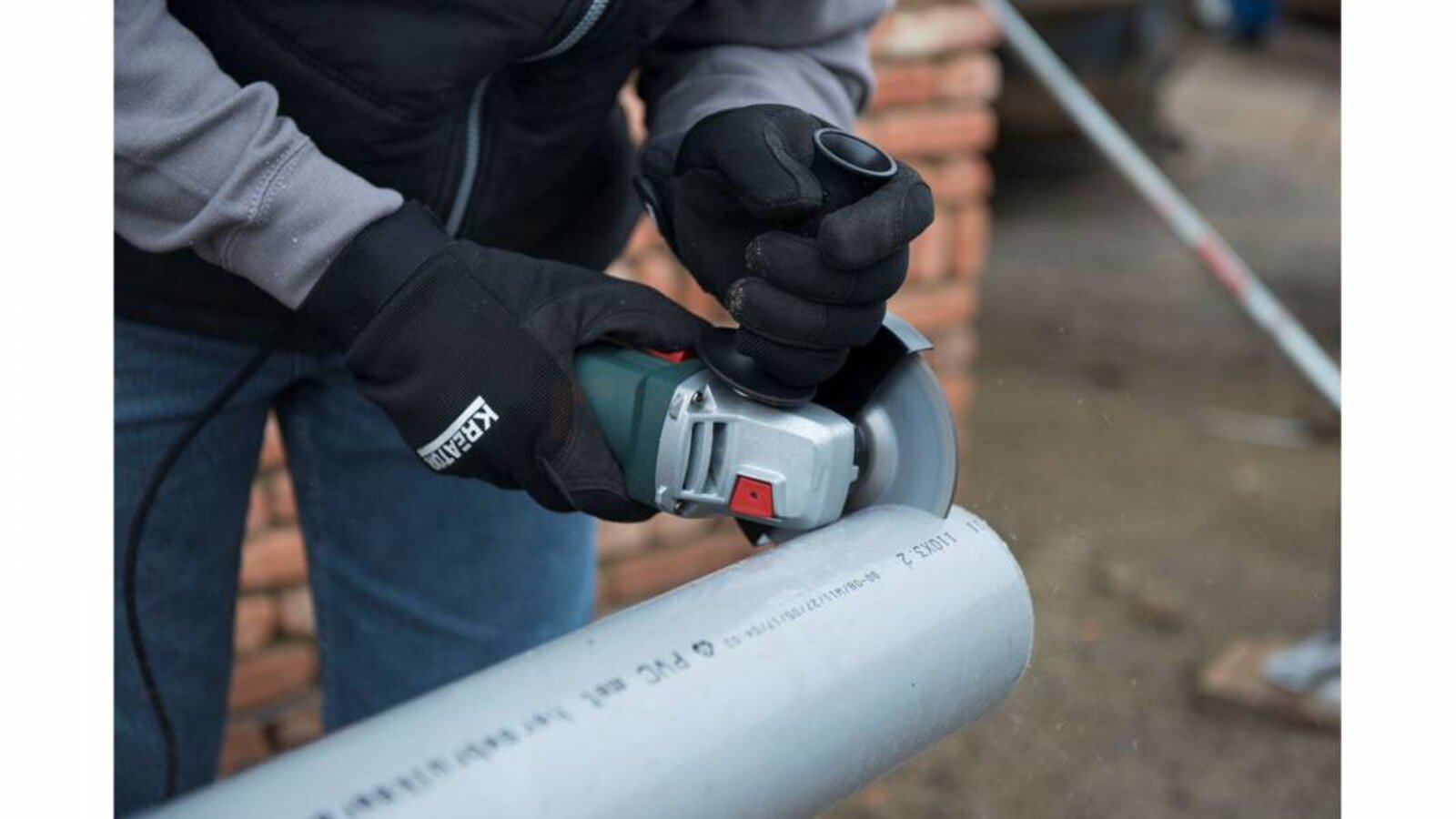 Pildil on näha, kuidas inimene kasutab nurklihvija PowerPlus POWP1020 abil halli toru lõikamist.