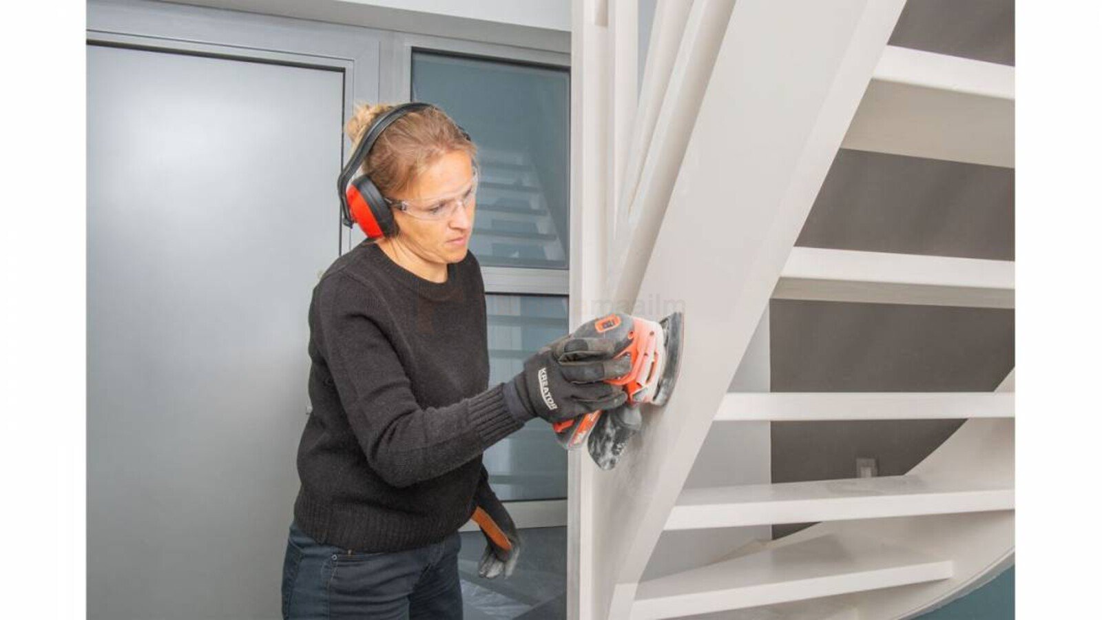 Pildil on naine, kes lihvib treppi akukolmnurklihvija Powerplus Dualpower abil, kandes samal ajal kaitseprille ja...
