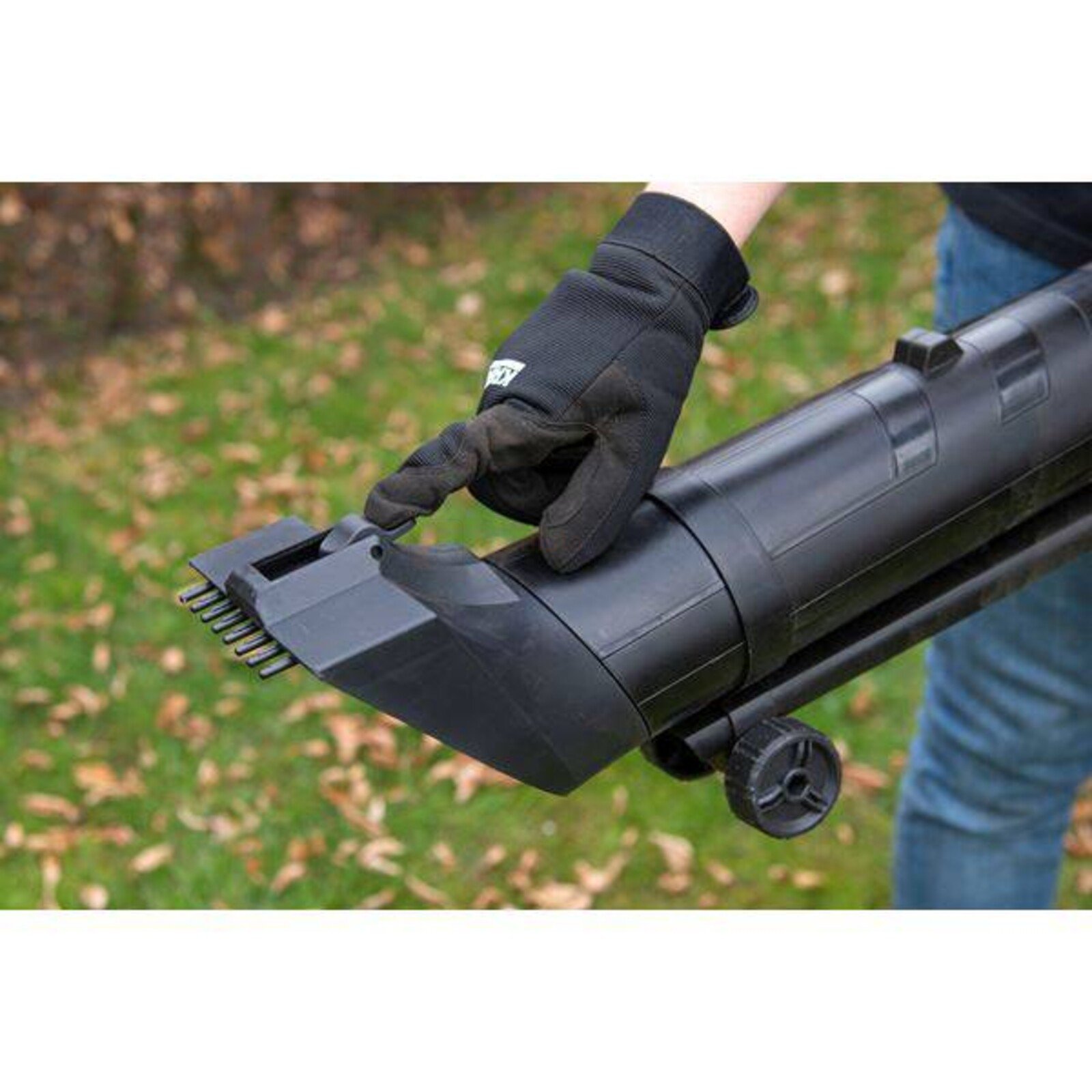 Pildil on näha, kuidas inimene kasutab Powerplus X lehepuhur-imurit POWXG4038, mille otsas on hambad ja millel on rattad.