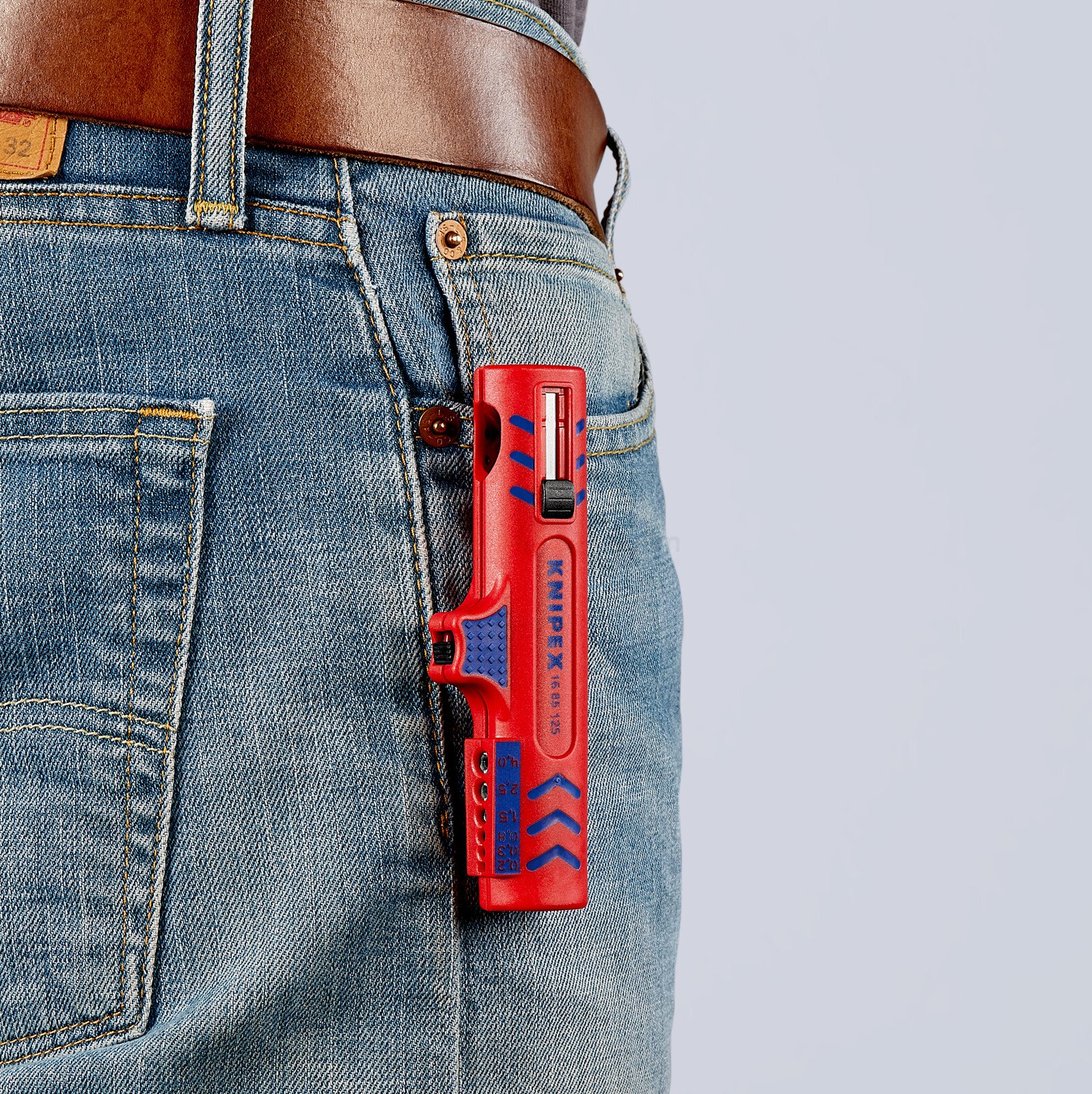 Pildil on Knipex kaablikoorija, mis on kinnitatud teksapükste taskusse.