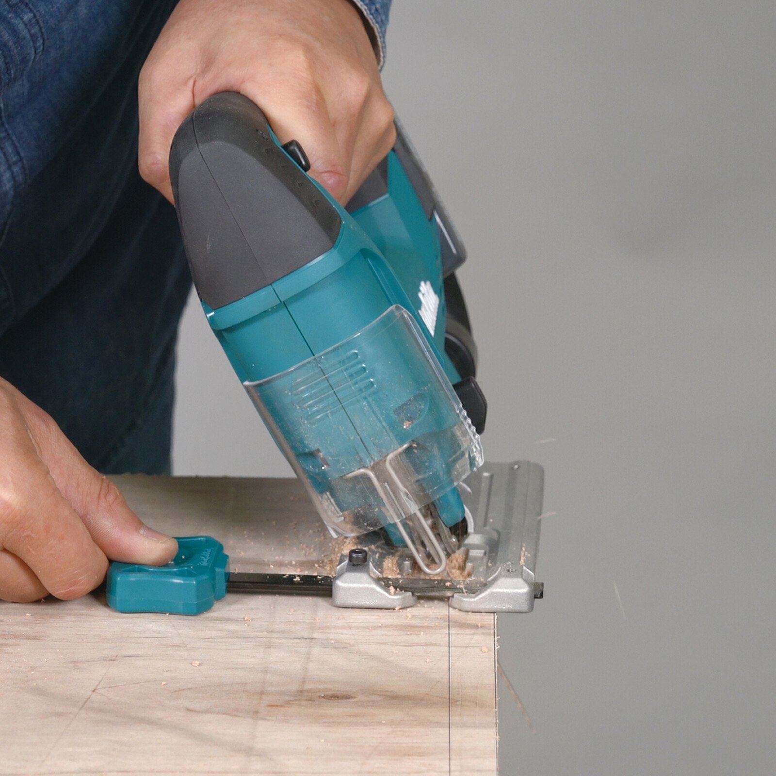 Pildil on näha, kuidas inimene kasutab Makita DJV186 akutikksaega, mille külge on kinnitatud külg- ja sirkeljuhtimistugi...