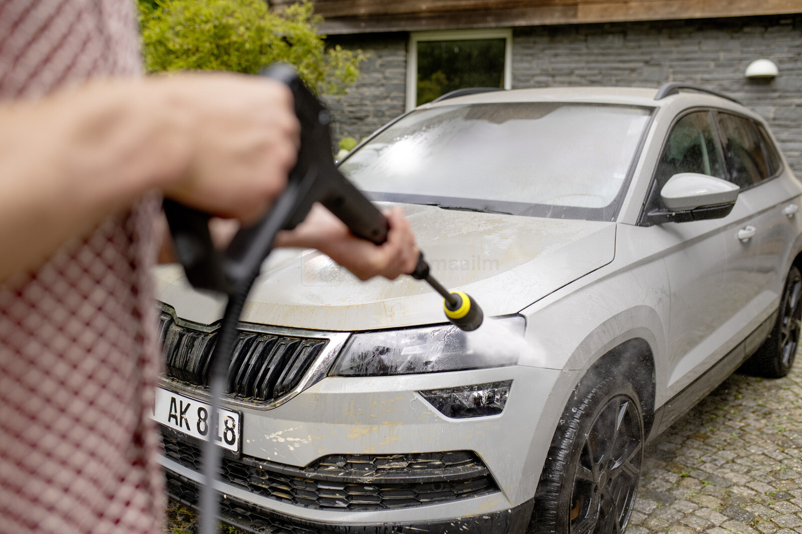 Pildil on näha, kuidas inimene peseb Kärcher K 7 Comfort Premium Home survepesuriga hõbedast autot.