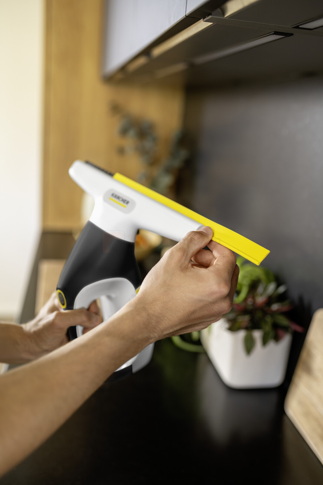 Pildil on näha inimene, kes kasutab Kärcher aknapesurit WV 3 Comfort Care'i, pühkides sellega tööpinda.