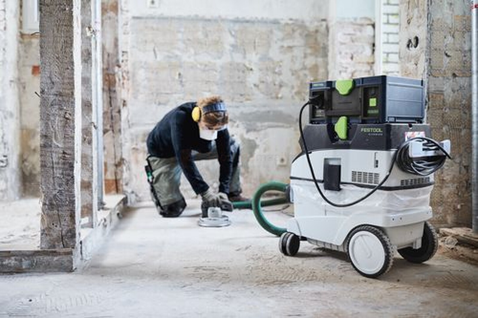 Pildil on ehitustööline, kes kasutab Festool mobiilset akupanka SYS-PowerStation SYS-PST 1500 Li HP, et lihvida põrandat...