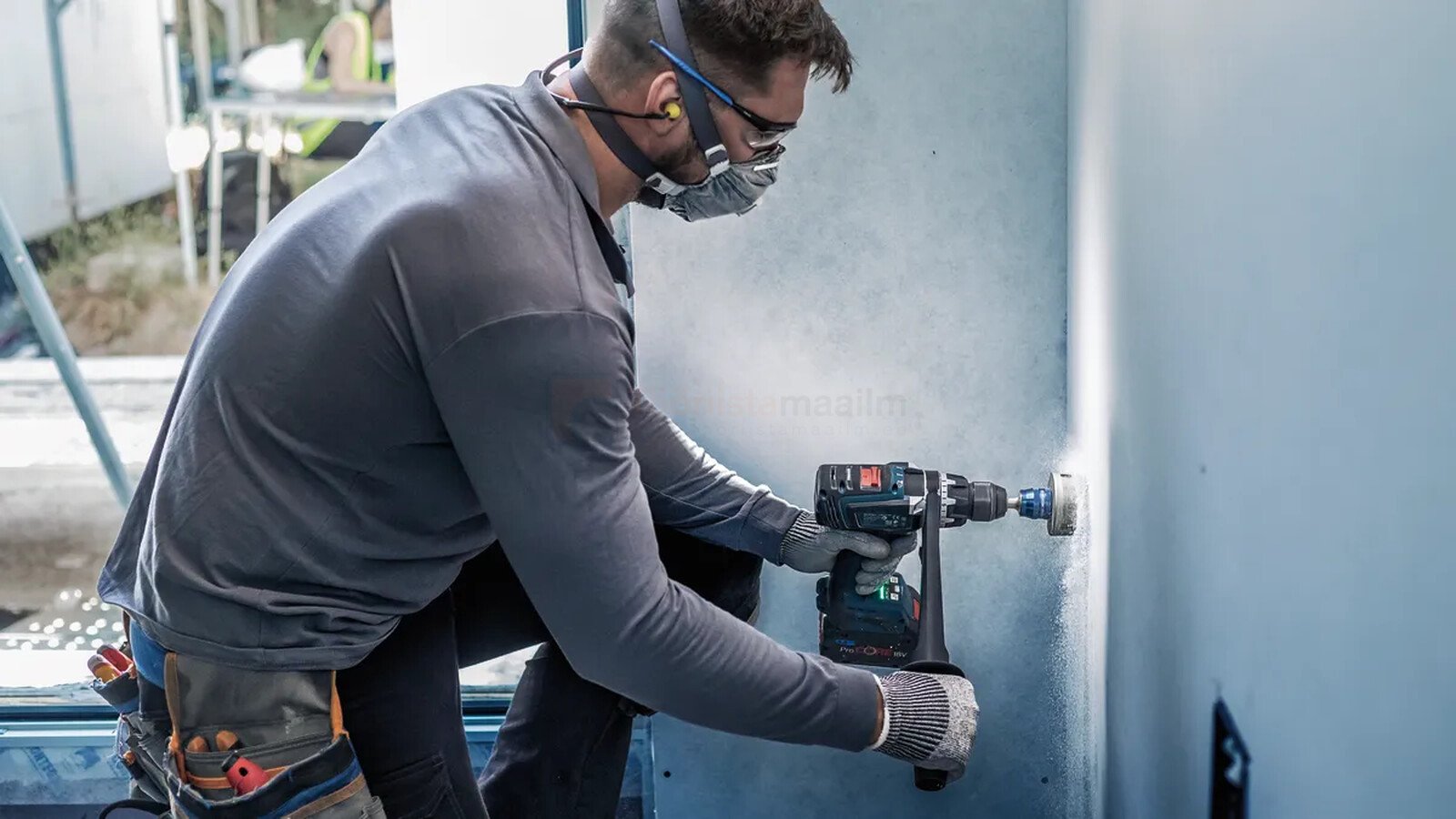 Pildil on mees, kes kasutab Bosch augusaagide komplekti, et teha auku seina.