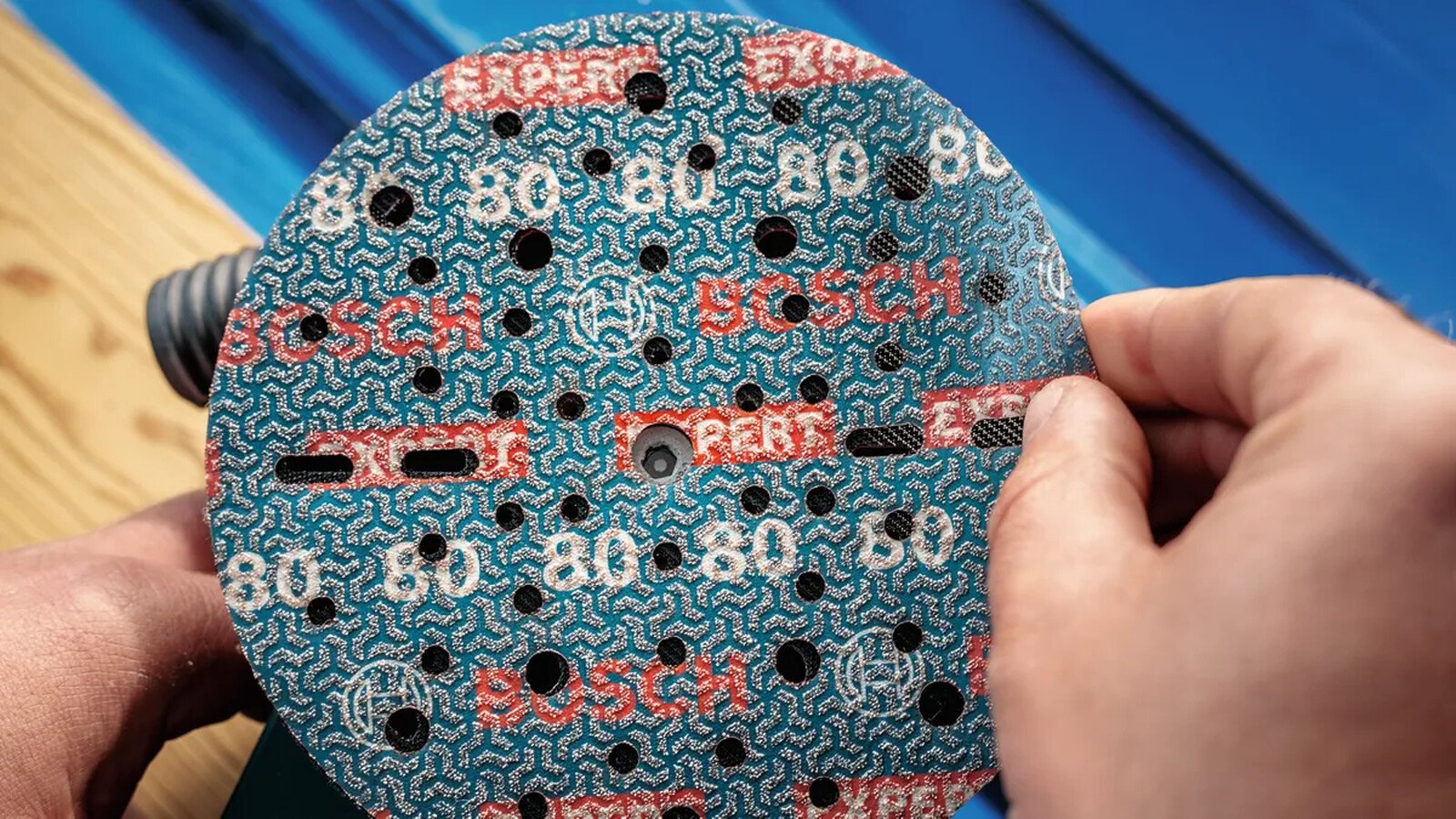 Pildil on näha, kuidas inimene paigaldab Bosch EXPERT O780 150 mm fooliumlihvketast.