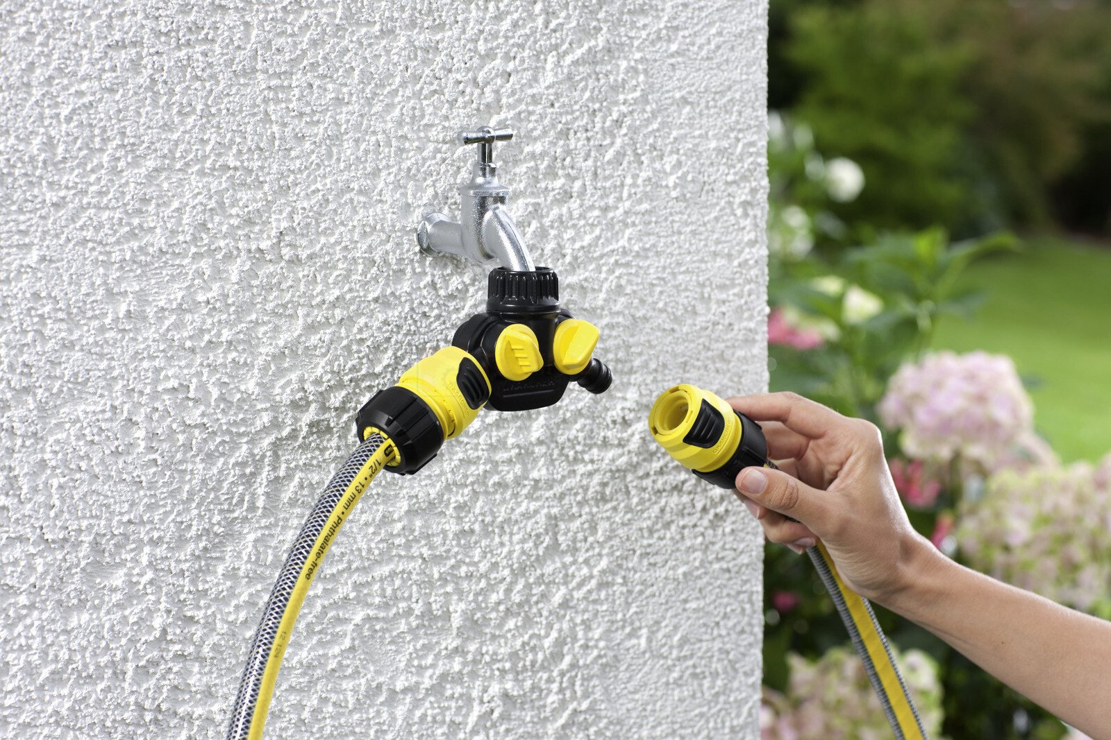 Pildil on näha Kärcher universaalne vooliku üleminek Plus, mis on ühendatud kraaniga ja voolikuga, samal ajal kui keegi...