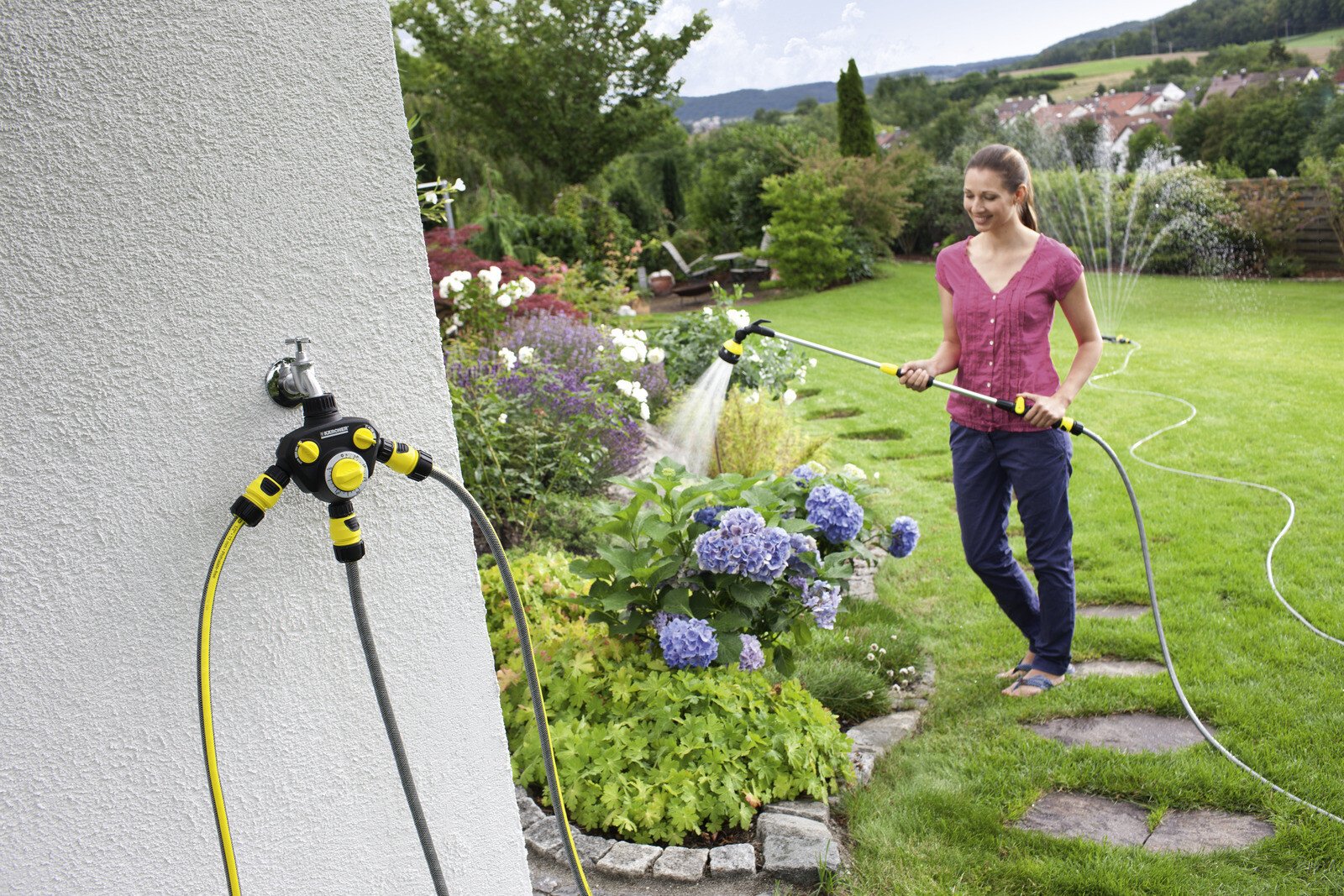 Pildil on näha Kärcher kastmiskell WT 2, mis on ühendatud kraaniga ja võimaldab naisel aeda kasta.