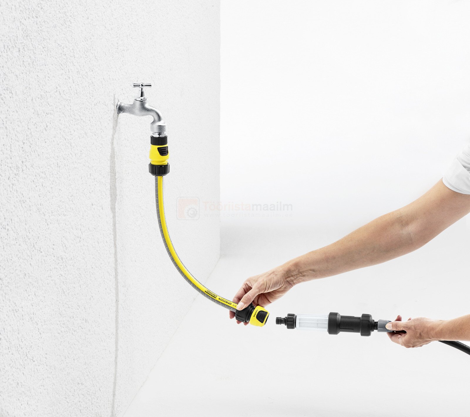 Pildil on näha, kuidas inimene ühendab Kärcher rõhureduktor-osakeste filtrit voolikuga, mis on ühendatud kraaniga.