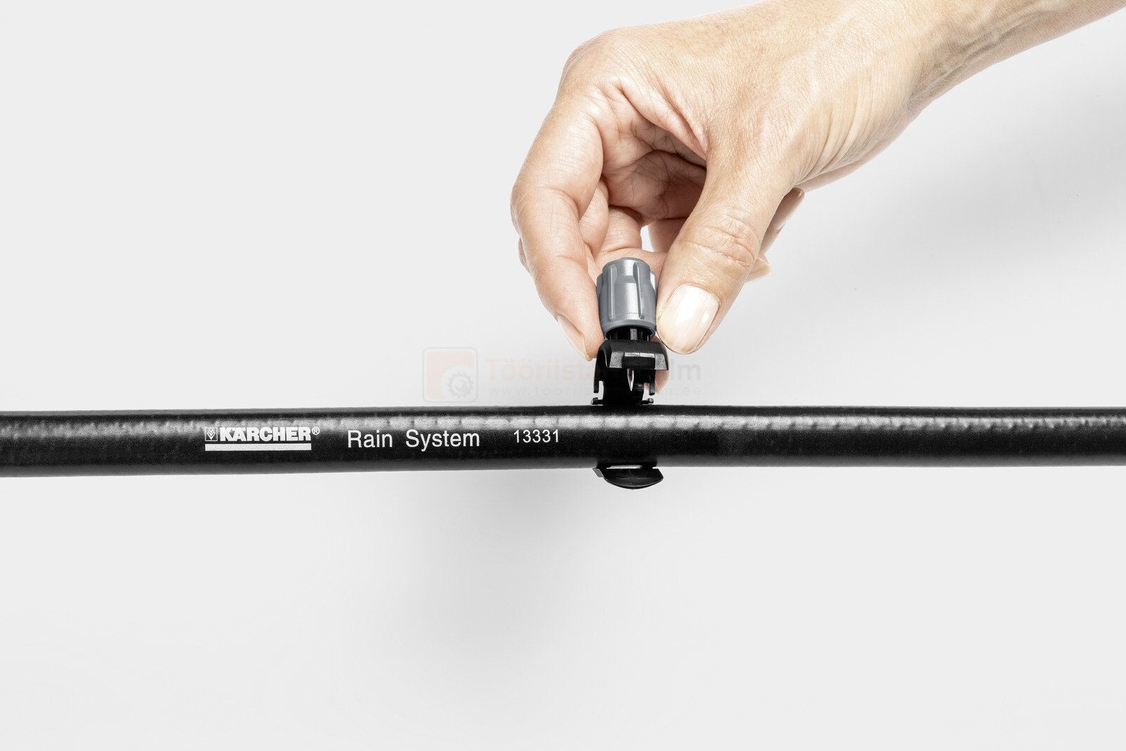 Pildil on näha, kuidas inimene paigaldab Kärcheri tilkumisotsikut mustale voolikule.