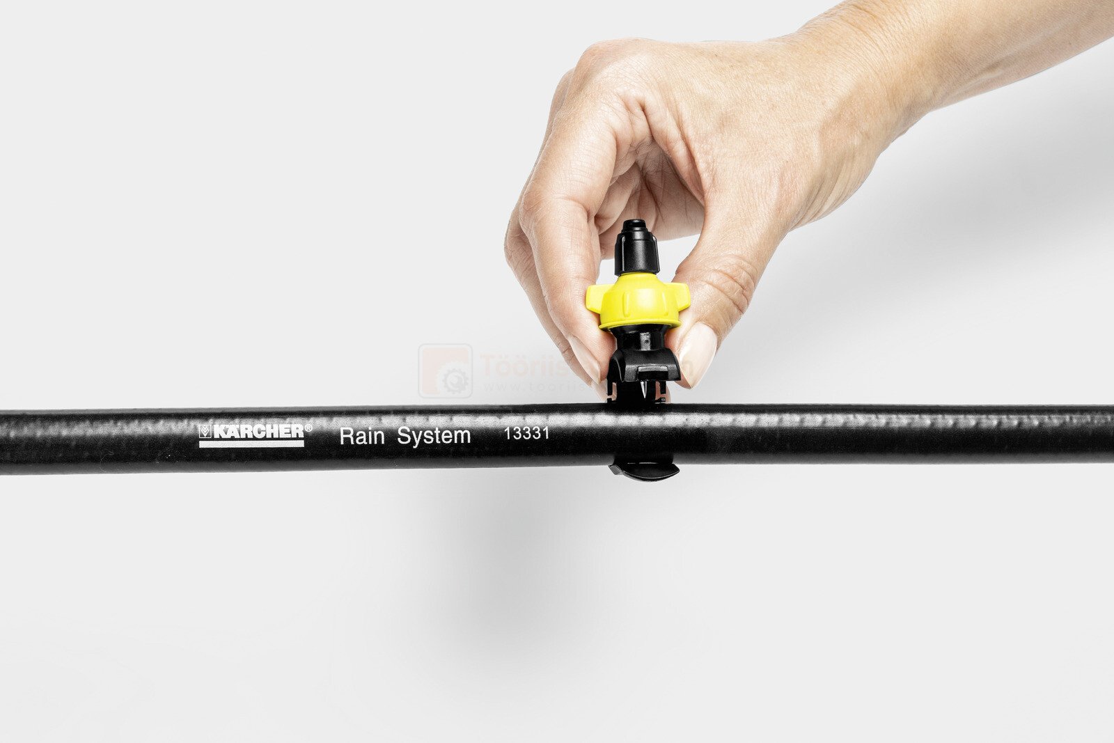 Pildil on näha, kuidas inimene paigaldab Kärcheri mikropihustusotsikute komplekti osi mustale torule.