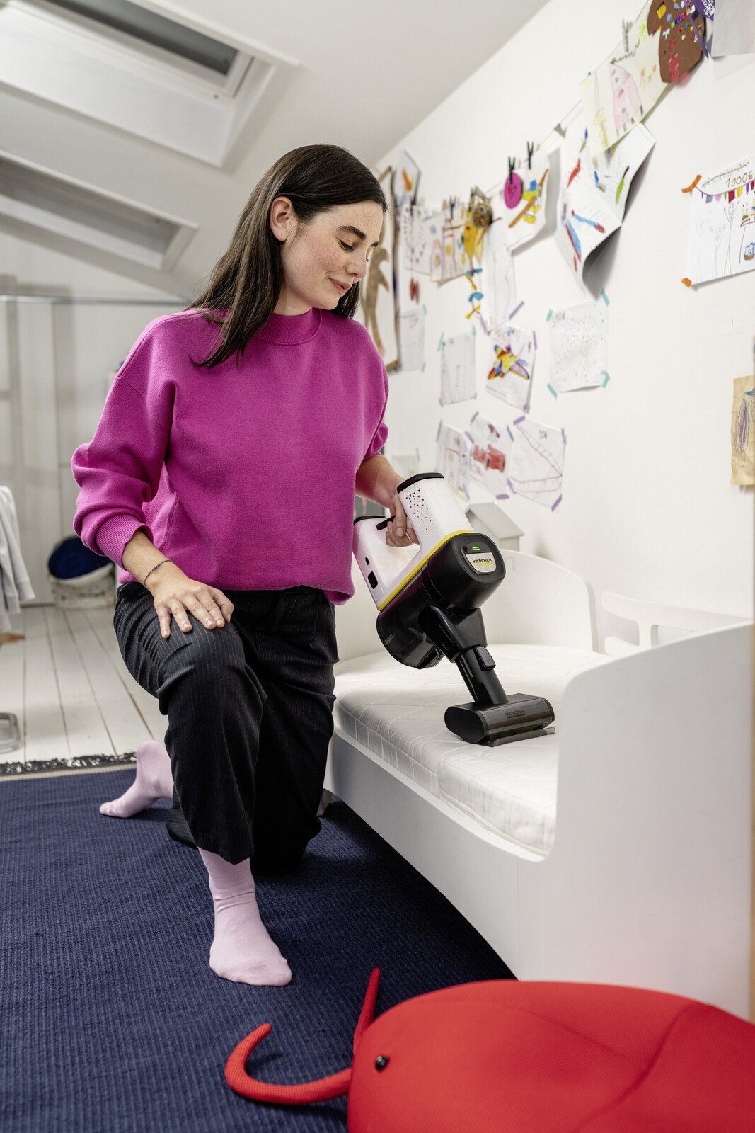 Pildil on naine, kes kasutab Kärcheri mini turboharja, et puhastada voodit.