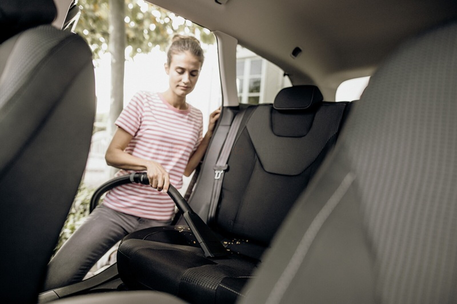 Pildil on naine, kes kasutab Kärcheri autootsakut autoistmete puhastamiseks.