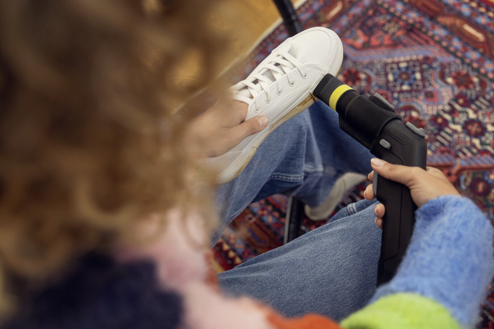 Pildil on näha, kuidas inimene puhastab valget tossu Kärcher Shoe!Cleaner otsikuga, mis on mõeldud SE tekstiilipesuritele.