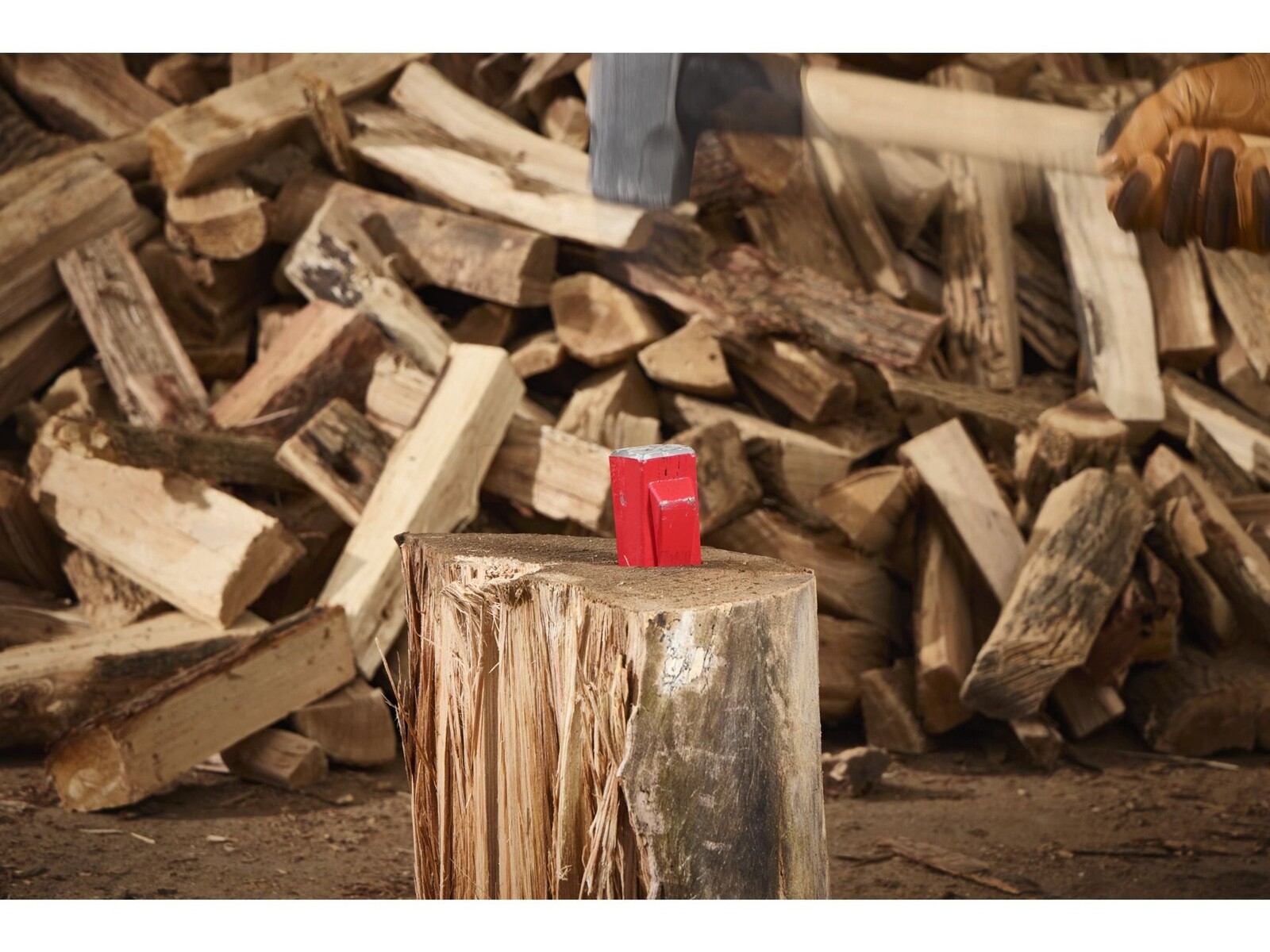 Pildil on Milwaukee puulõhkumiskiil 200 mm, mis on asetatud puupakule ja millega ollakse valmis puid lõhkuma.