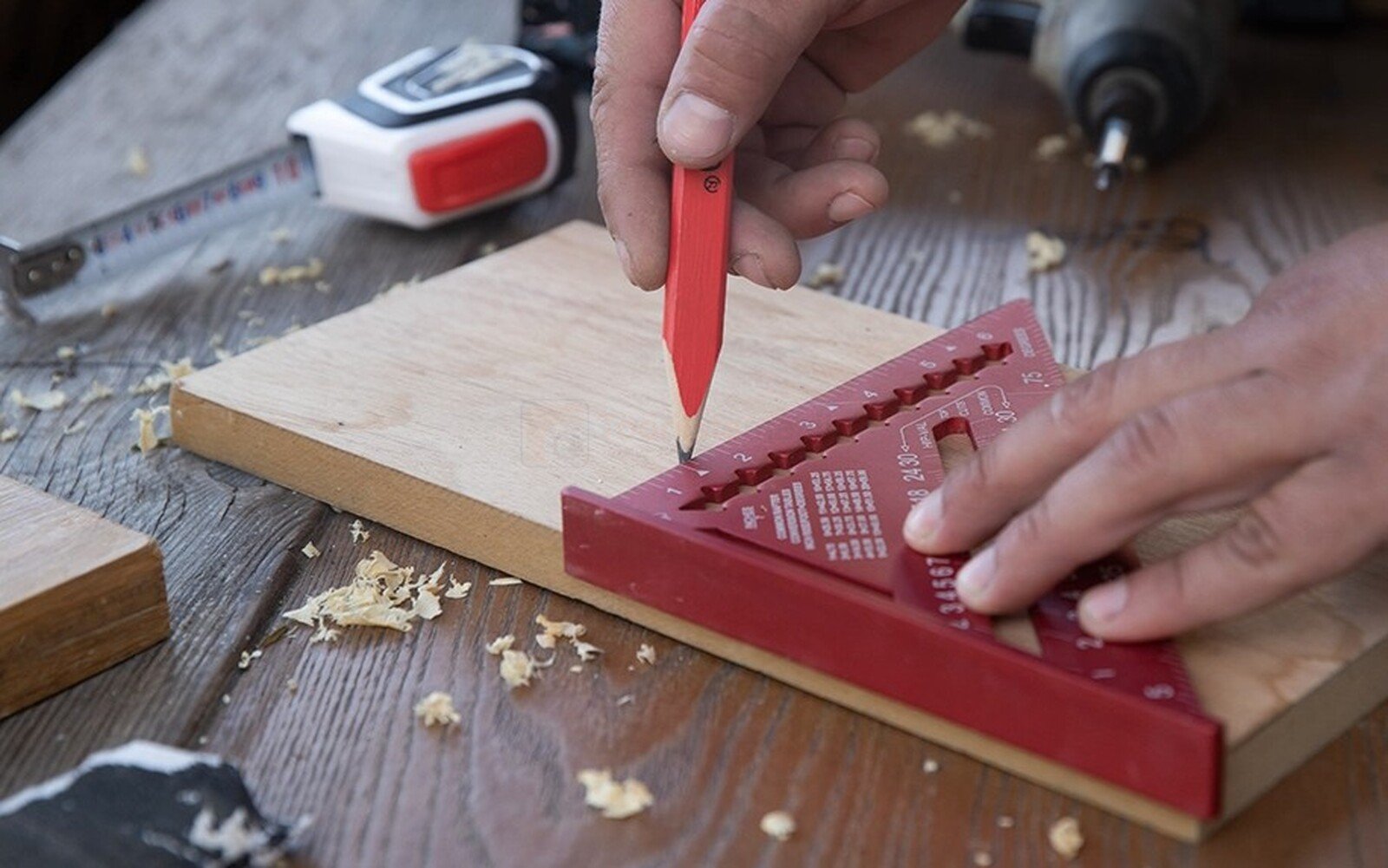 Pildil on näha, kuidas mees kasutab Kapro puusepa nurgikut 300 mm puidutüki peale joone tõmbamiseks.