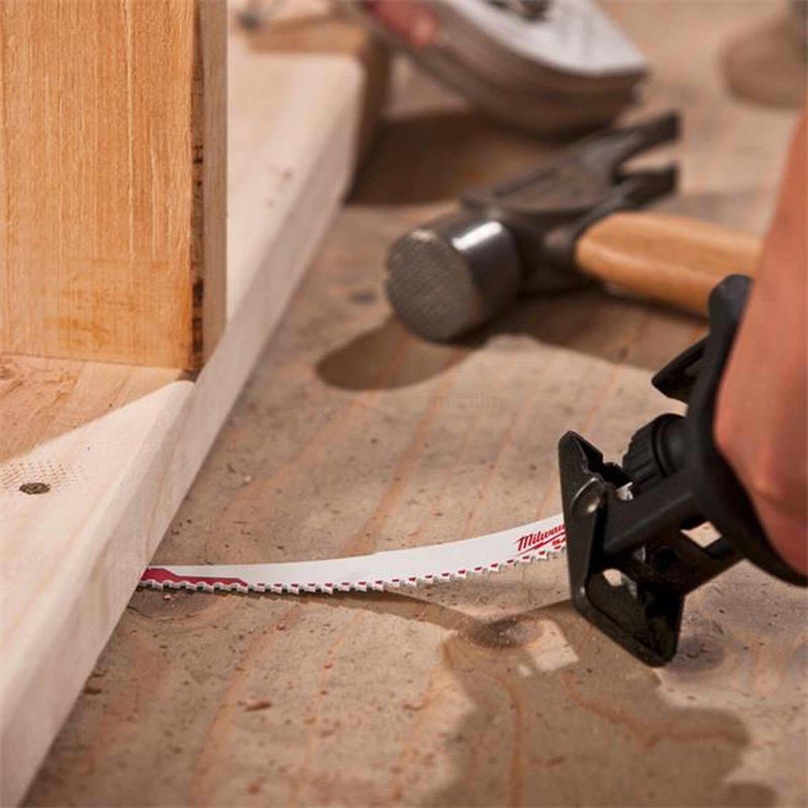 Pildil on näha, kuidas Milwaukee otssaetera AX 300 mm 5 TPI, mis on mõeldud naeltega puidule, lõikab puitu, samal ajal...