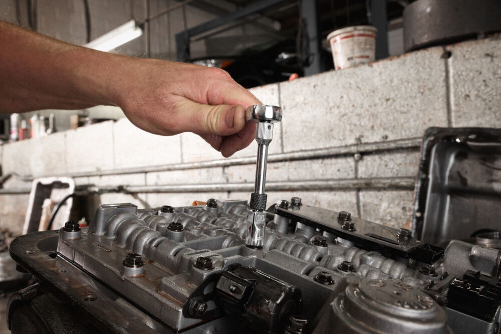 Pildil on mehaanik, kes kasutab Milwaukee 1/4" pikendust, et töötada auto osaga.