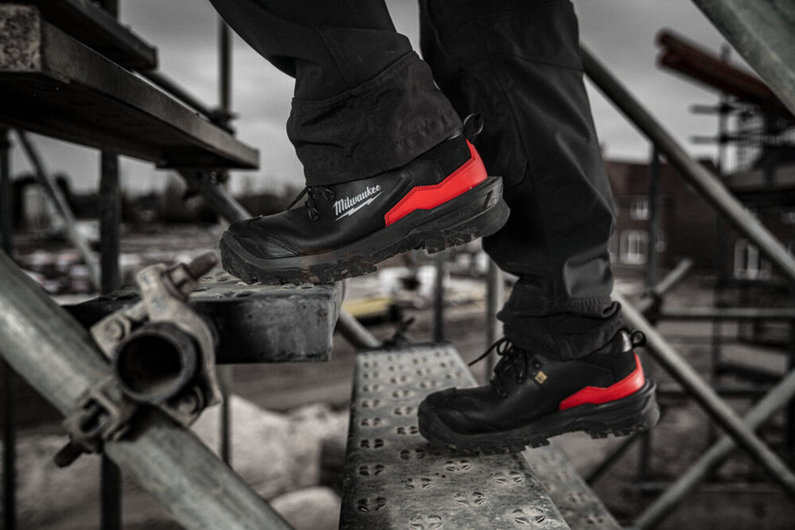 Pildil on näha Milwaukee turvajalatsid Armourtred™ S3S 1L110111W ESD HRO SC FO LG SR, mis on kantud ehitusplatsil, kus...