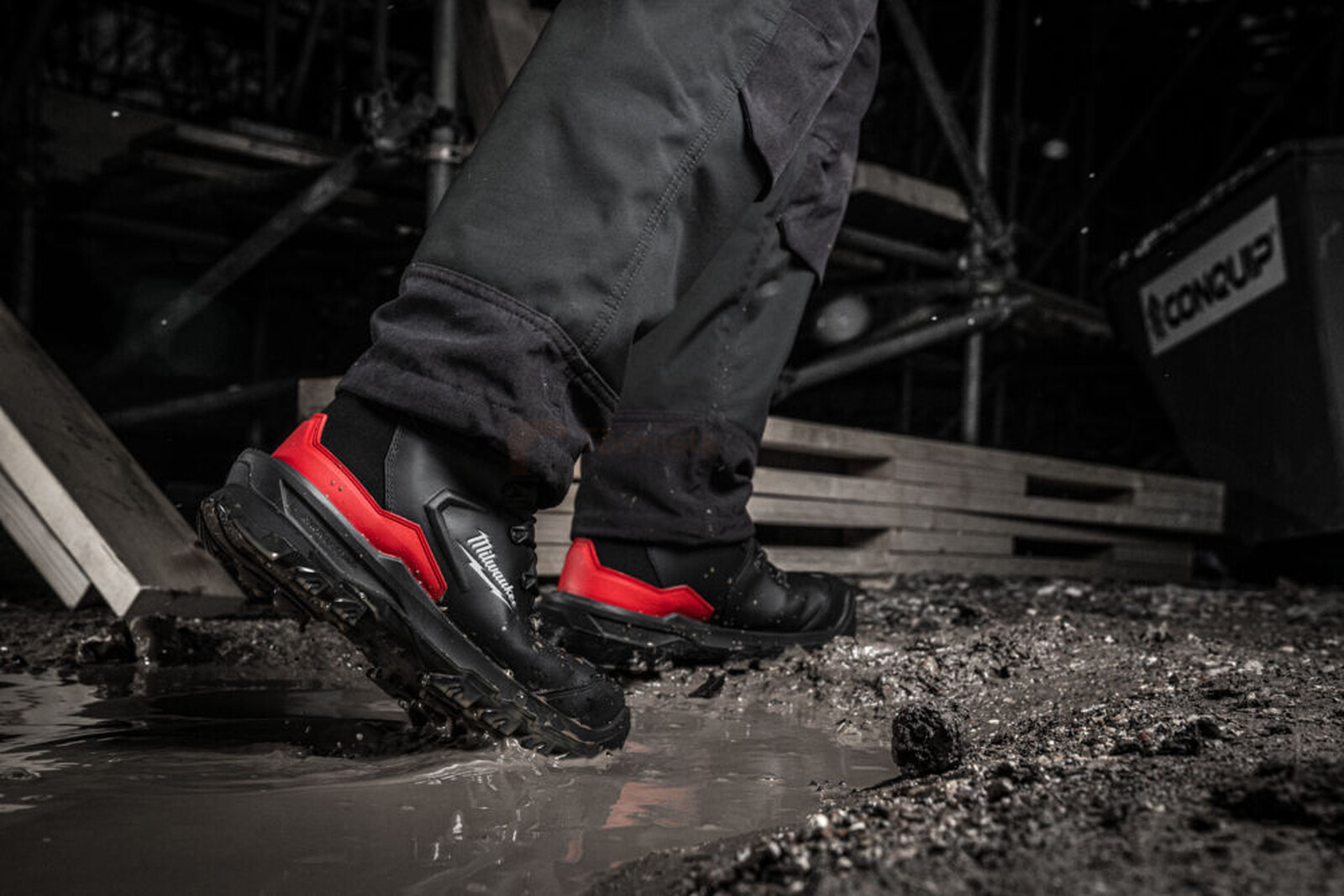 Pildil on näha, kuidas Milwaukee Armourtred™ S7S turvasaapad on kasutuses, astudes läbi loigu ehitusplatsil.