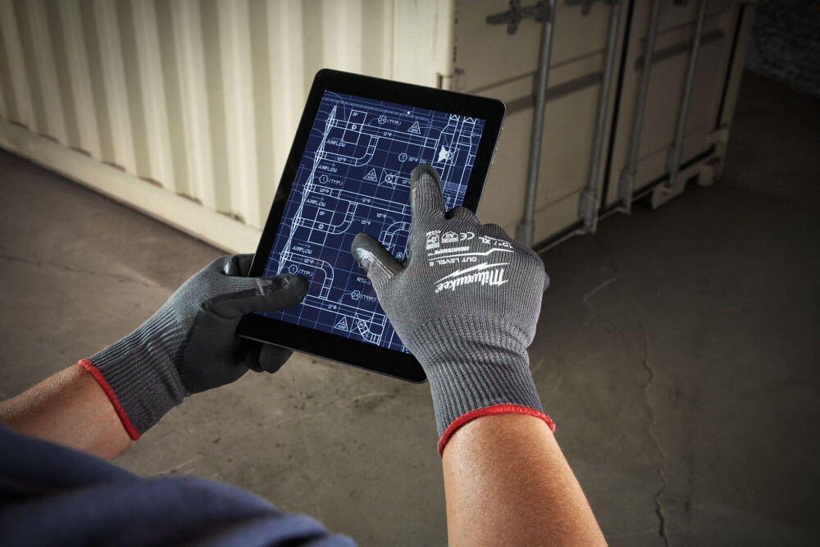 Pildil on Milwaukee lõikekindlus 5 kindad, mida kasutatakse tahvelarvuti ekraanil olevate plaanide vaatamiseks.