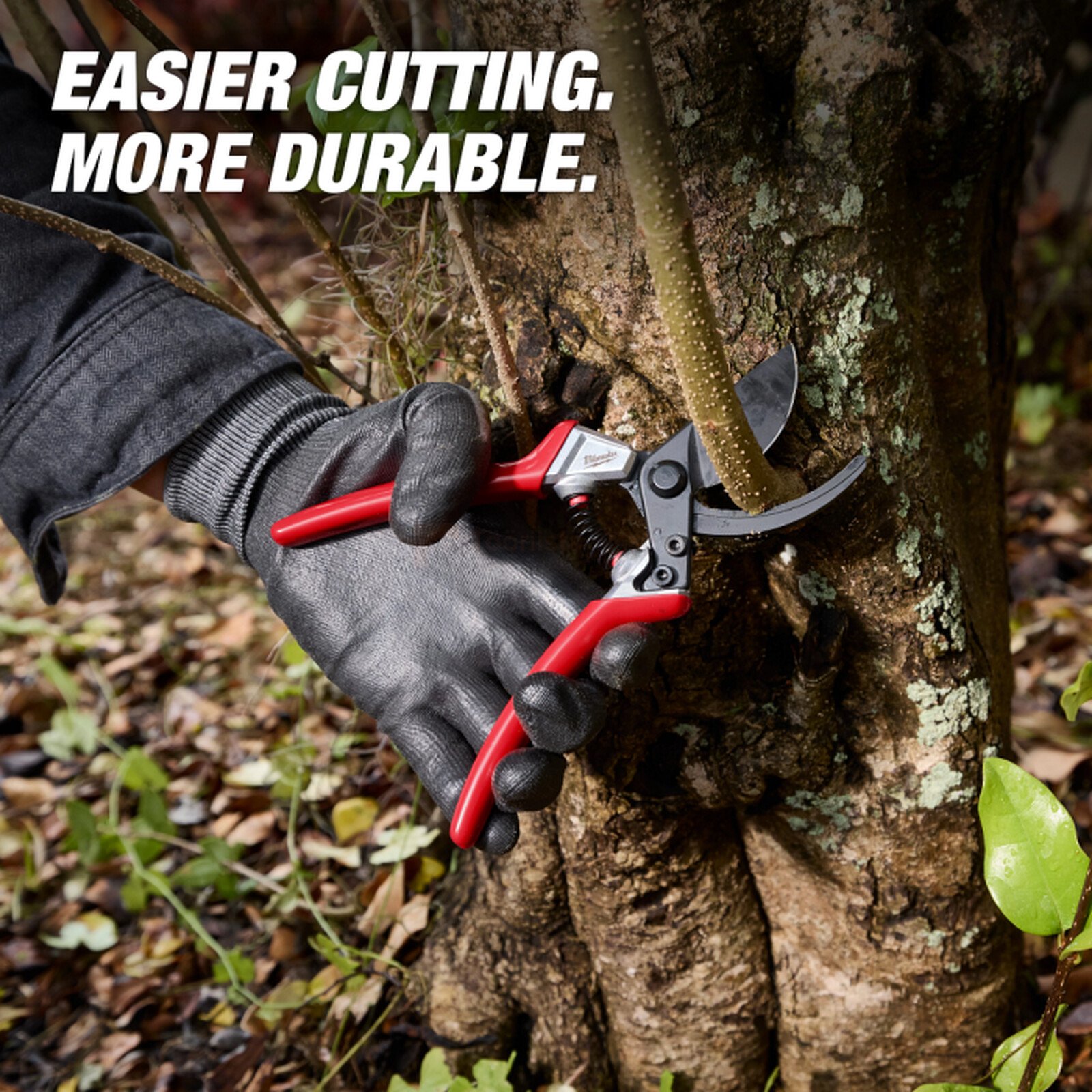 Pildil on Milwaukee oksakäärid, millega lõigatakse puuoksa, samal ajal kui kasutaja kannab musti kindaid.