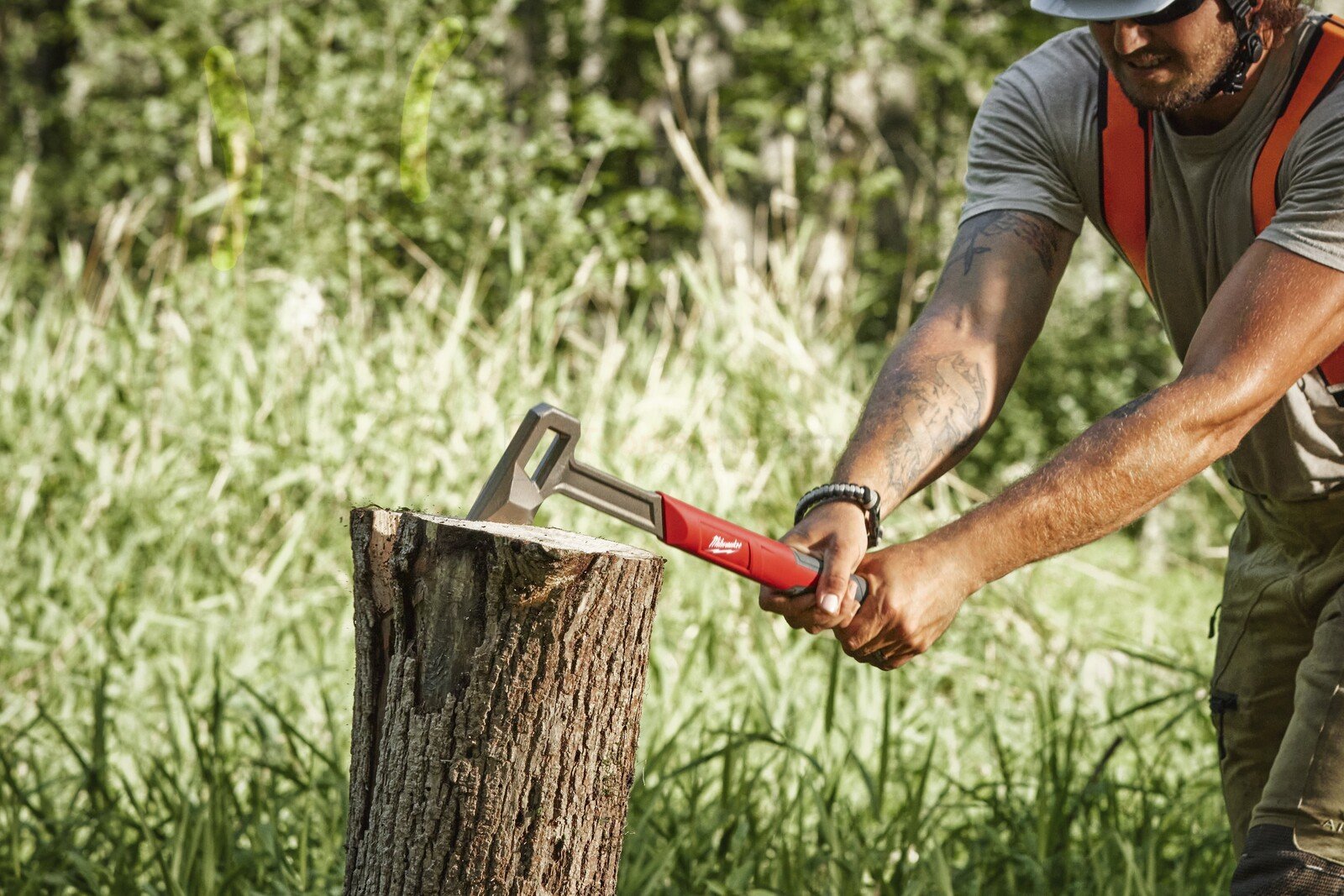 Pildil on mees, kes kasutab Milwaukee 40 cm kirvest puupaku lõhkumiseks.