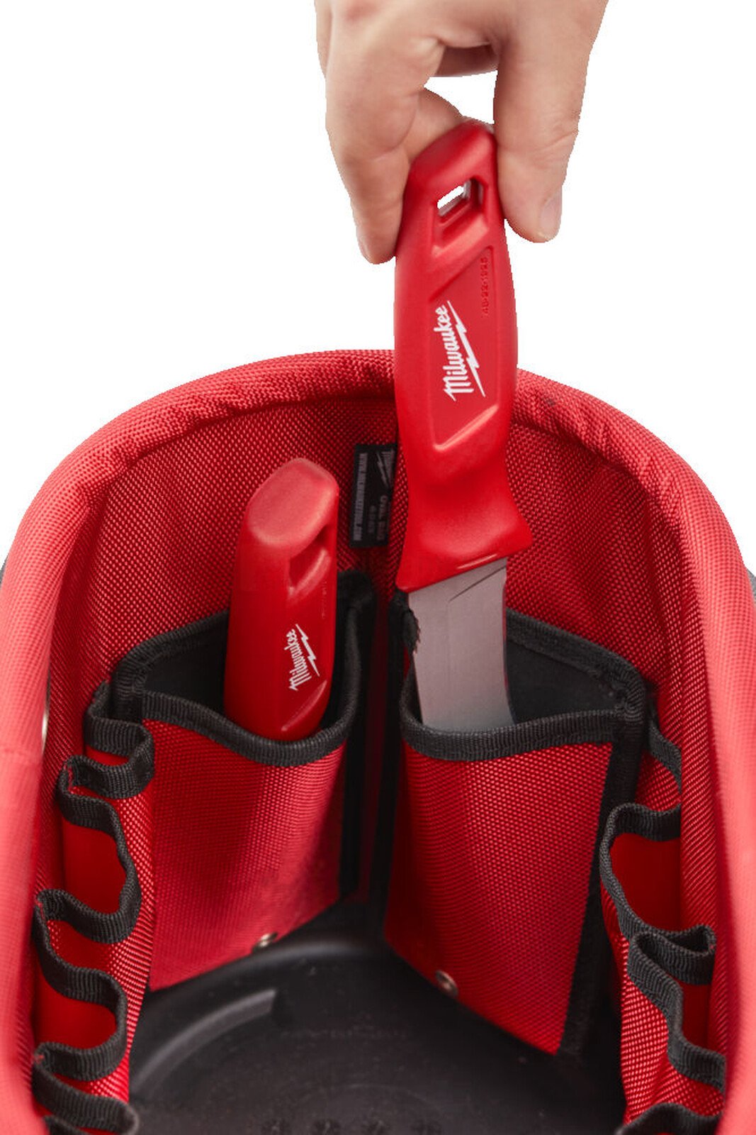 Pildil on Milwaukee ovaalse kandekoti sisu, kus on näha punaseid tööriistu, mis on paigutatud koti sisemistesse taskutesse.