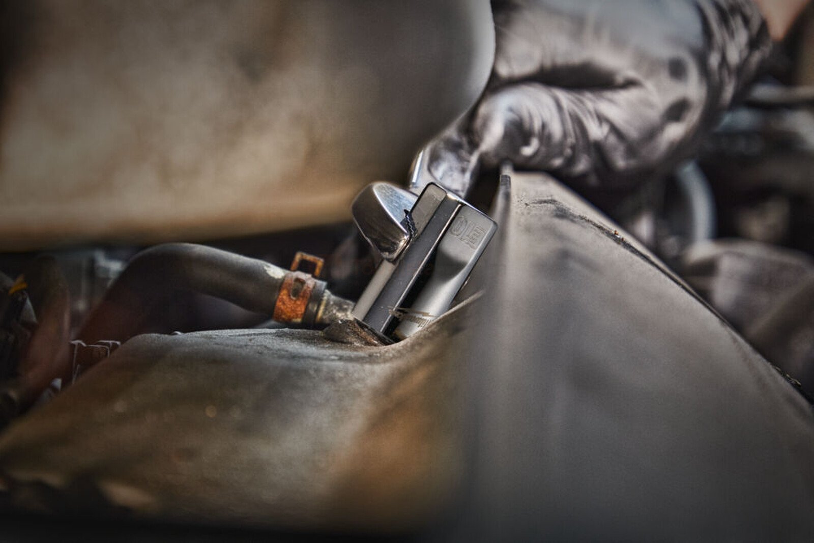 Pildil on Milwaukee E-Torx padrunite komplektiga seotud tegevus, kus musta kindaga käsi töötab mingi detaili küljes.