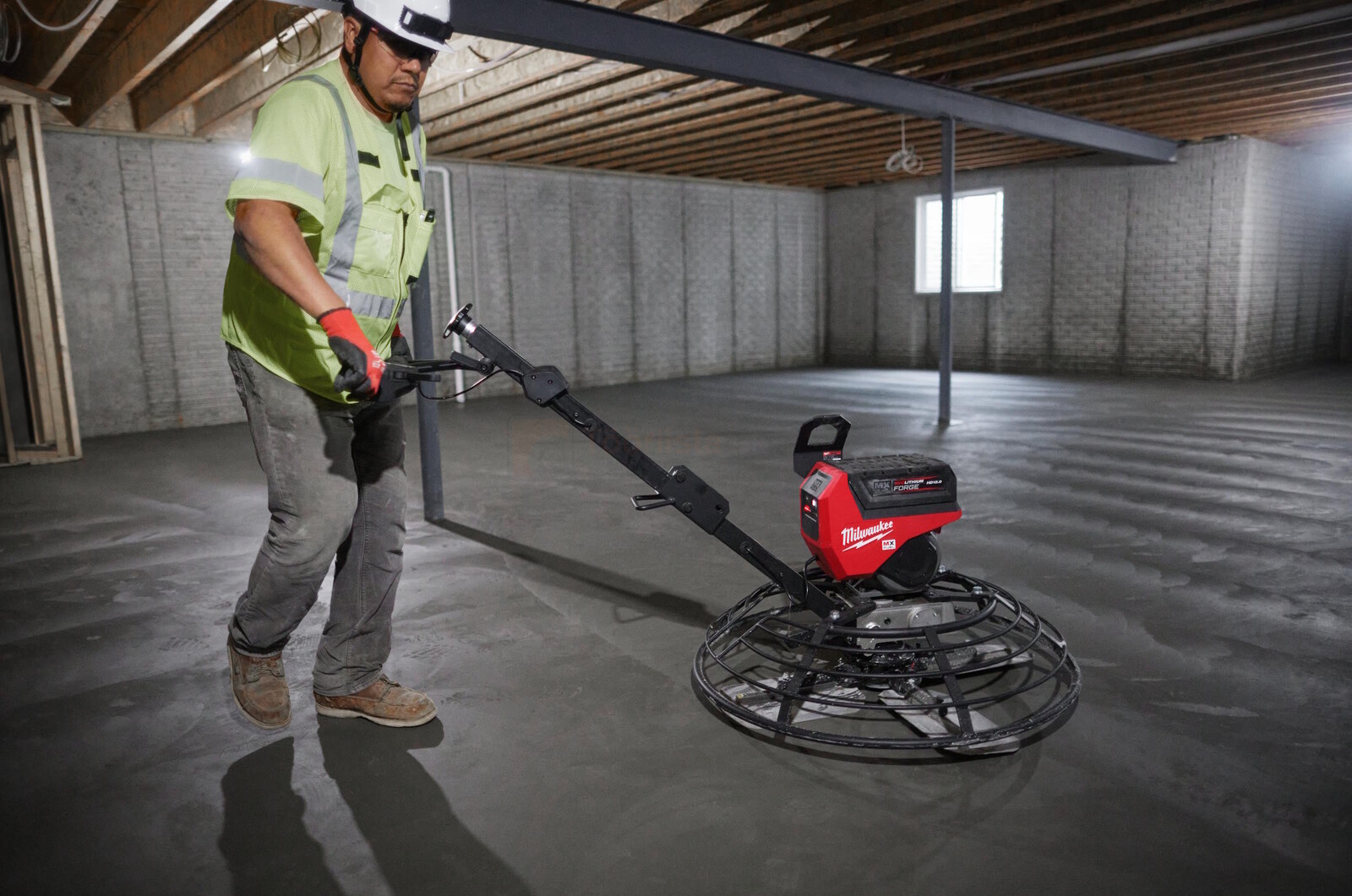Pildil on ehitustööline, kes kasutab Milwaukee viimistlustera MXF WBT90 betoonisilurit, et siluda betoonpõrandat.