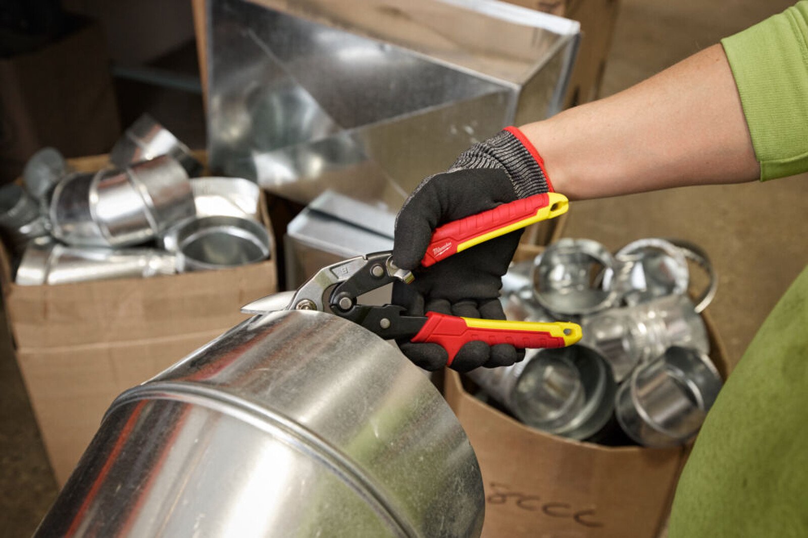 Pildil on näha, kuidas inimene kasutab Milwaukee tugevdatud plekikäärid, sirged, et lõigata metallist toru.