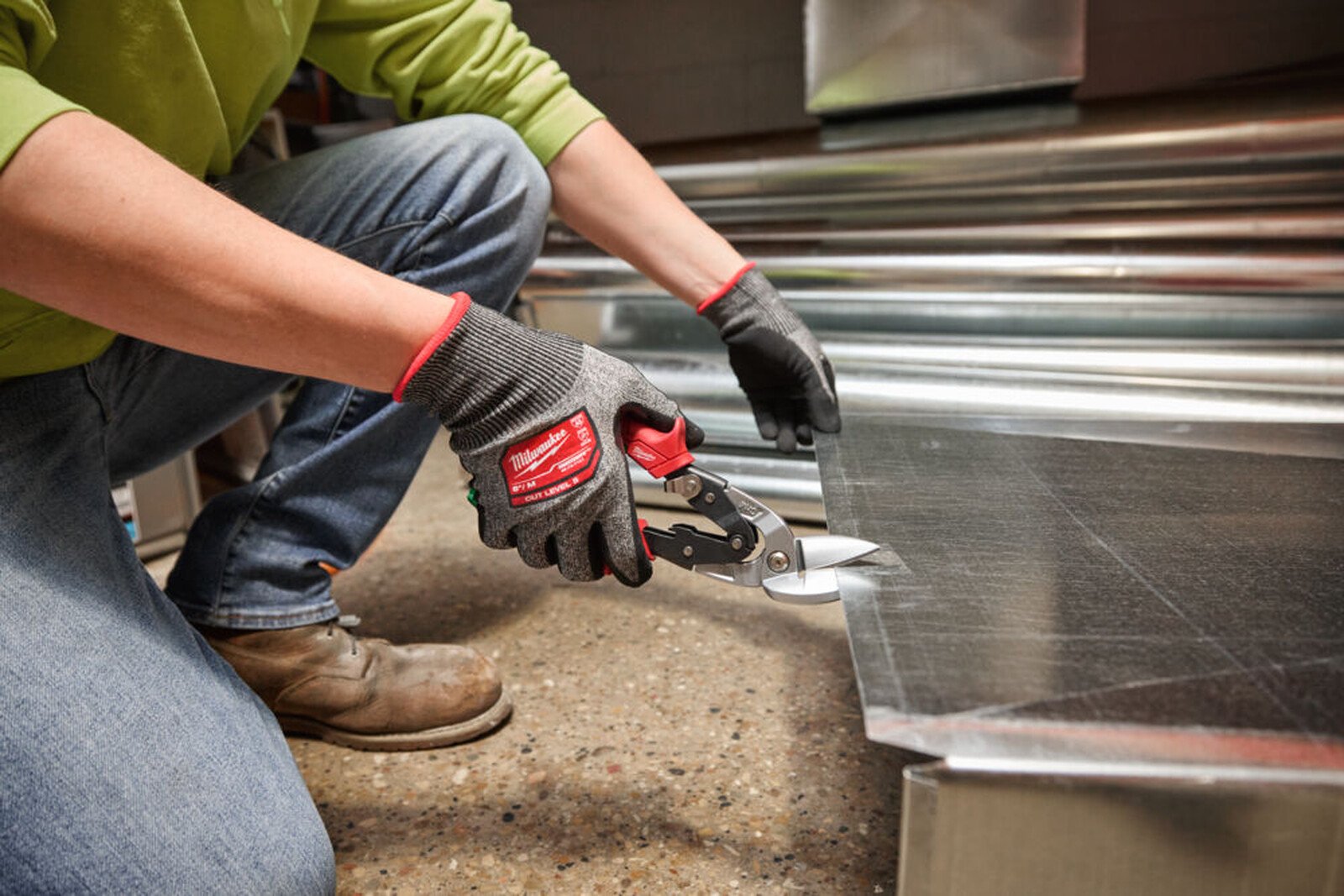 Pildil on inimene, kes kasutab Milwaukee nihkega plekikäärid, parem, et lõigata metallplekki.