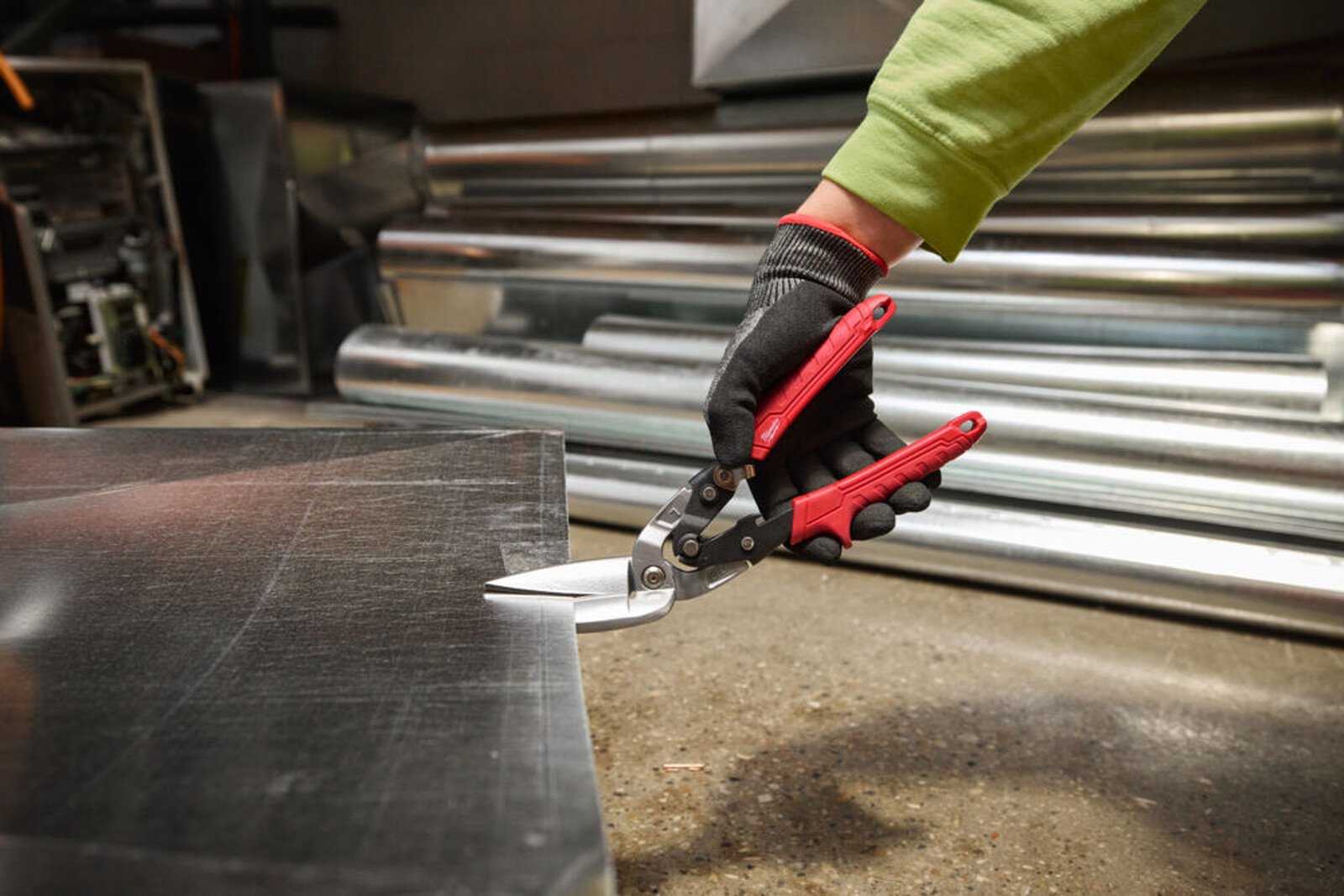 Pildil on näha, kuidas inimene lõikab Milwaukee nihkega pikkade plekikääridega vasakule metallplekki.