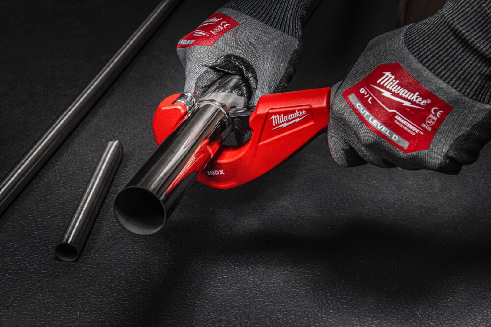 Pildil on näha, kuidas inimene kasutab Milwaukee torulõikurit 3-29 mm INOX torude lõikamiseks, hoides seda mõlema käega...