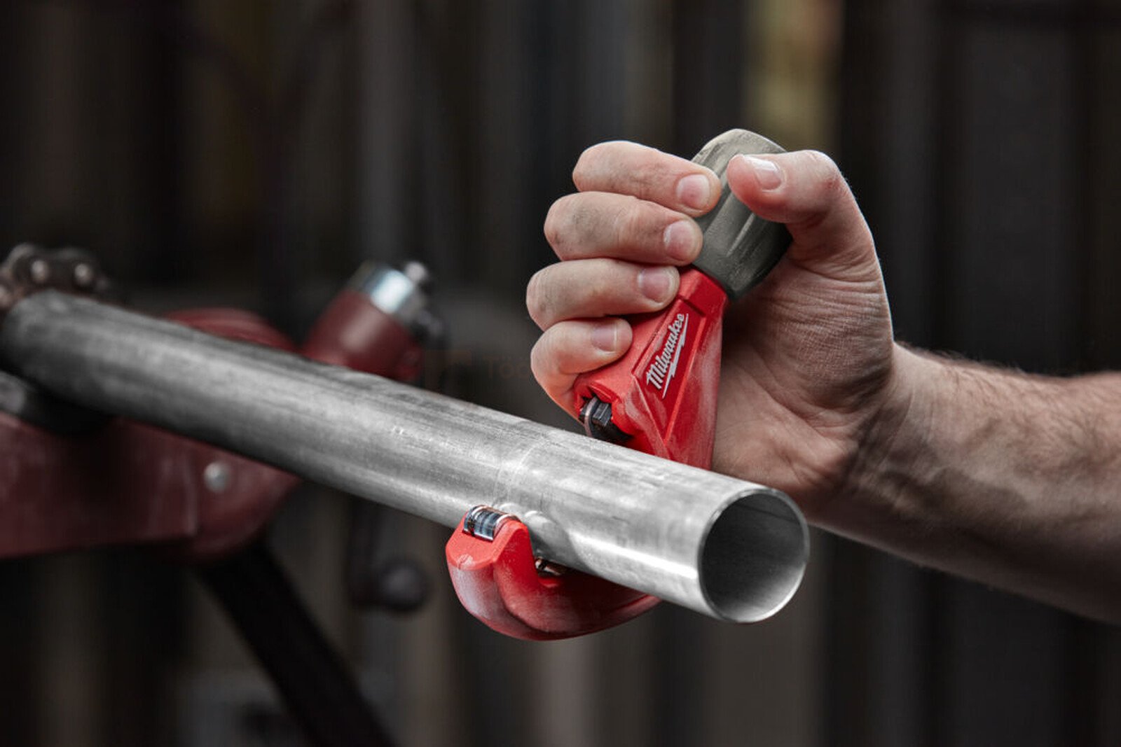 Pildil on mees, kes kasutab Milwaukee torulõikurit 3-42 mm INOX torudele, et lõigata metalltoru.