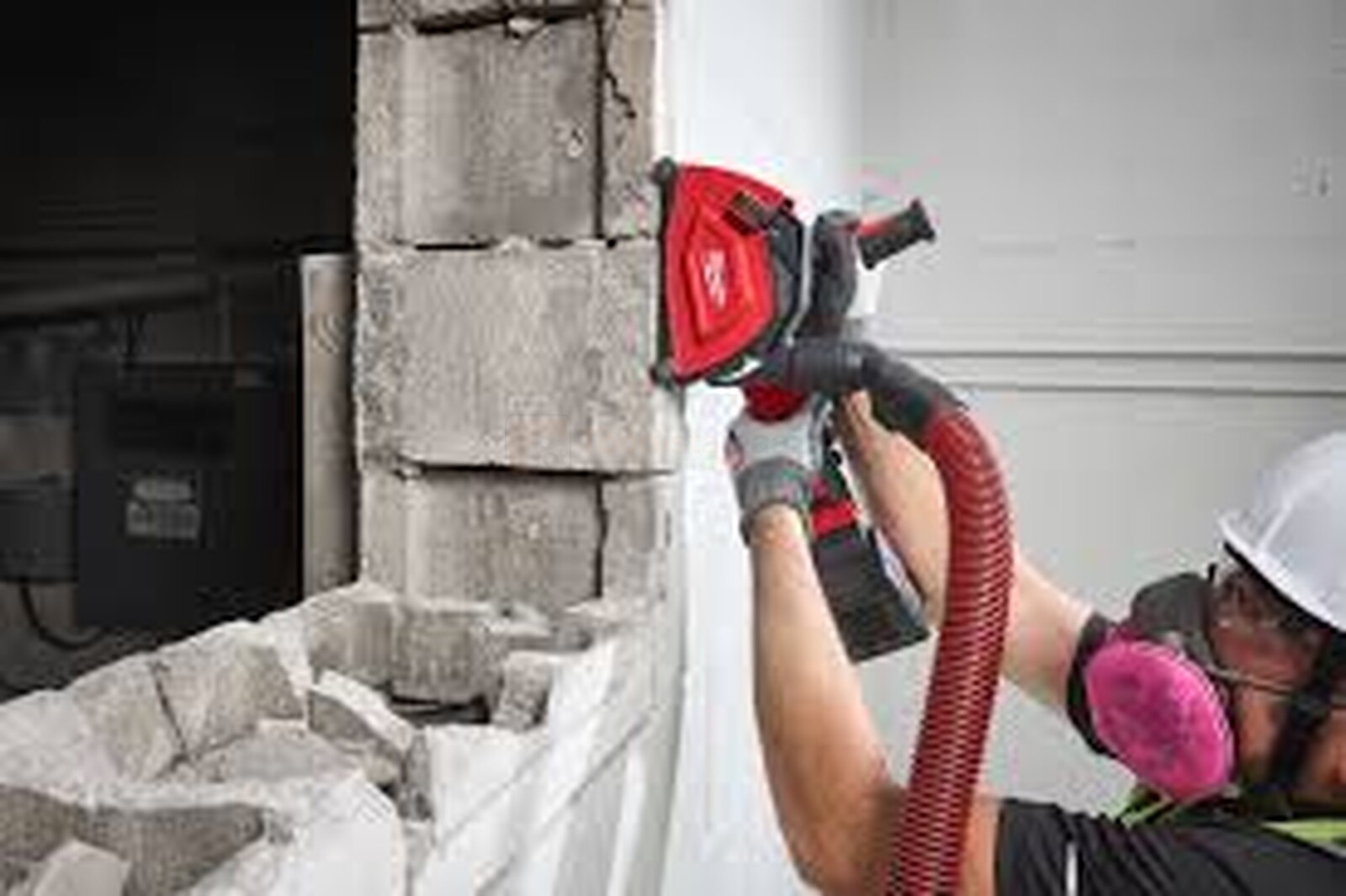 Pildil on ehitustöötaja, kes kasutab Milwaukee tolmukatet DSC125 koos nurklihvijaga, et lõigata betoonseina, samal ajal...