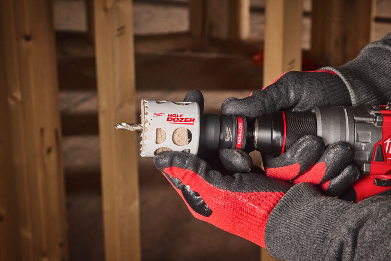 Pildil on näha, kuidas inimene kasutab Milwaukee augusae adapterit QUIK-LOK, et puurida augusae abil puitu.