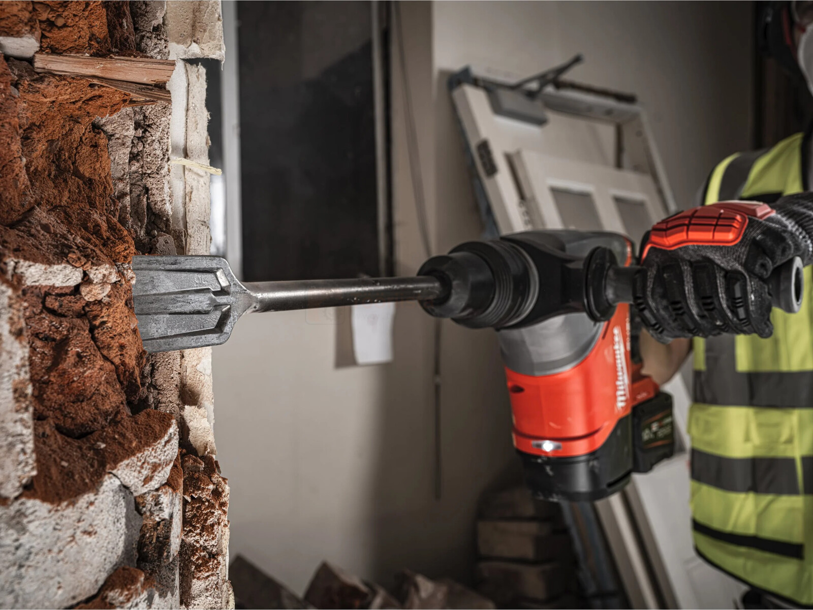 Pildil on ehitustöötaja, kes kasutab Milwaukee akupuurvasarat M18 FHACO540-0C, et lammutada seina.
