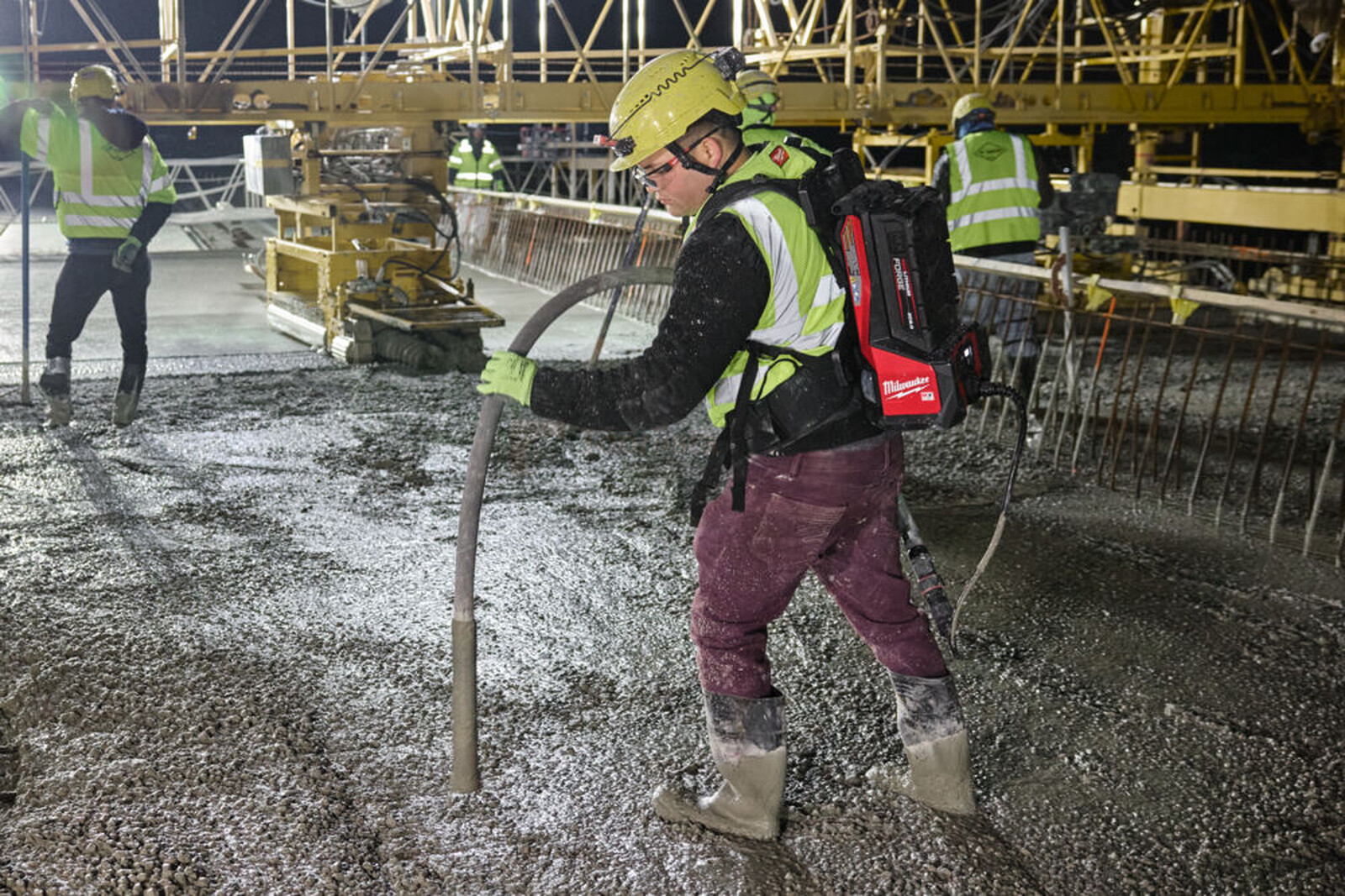 Pildil on ehitustöölised, kes kasutavad Milwaukee akubetoonivibraatorit MXF CVHF-0 betooni tihendamiseks.